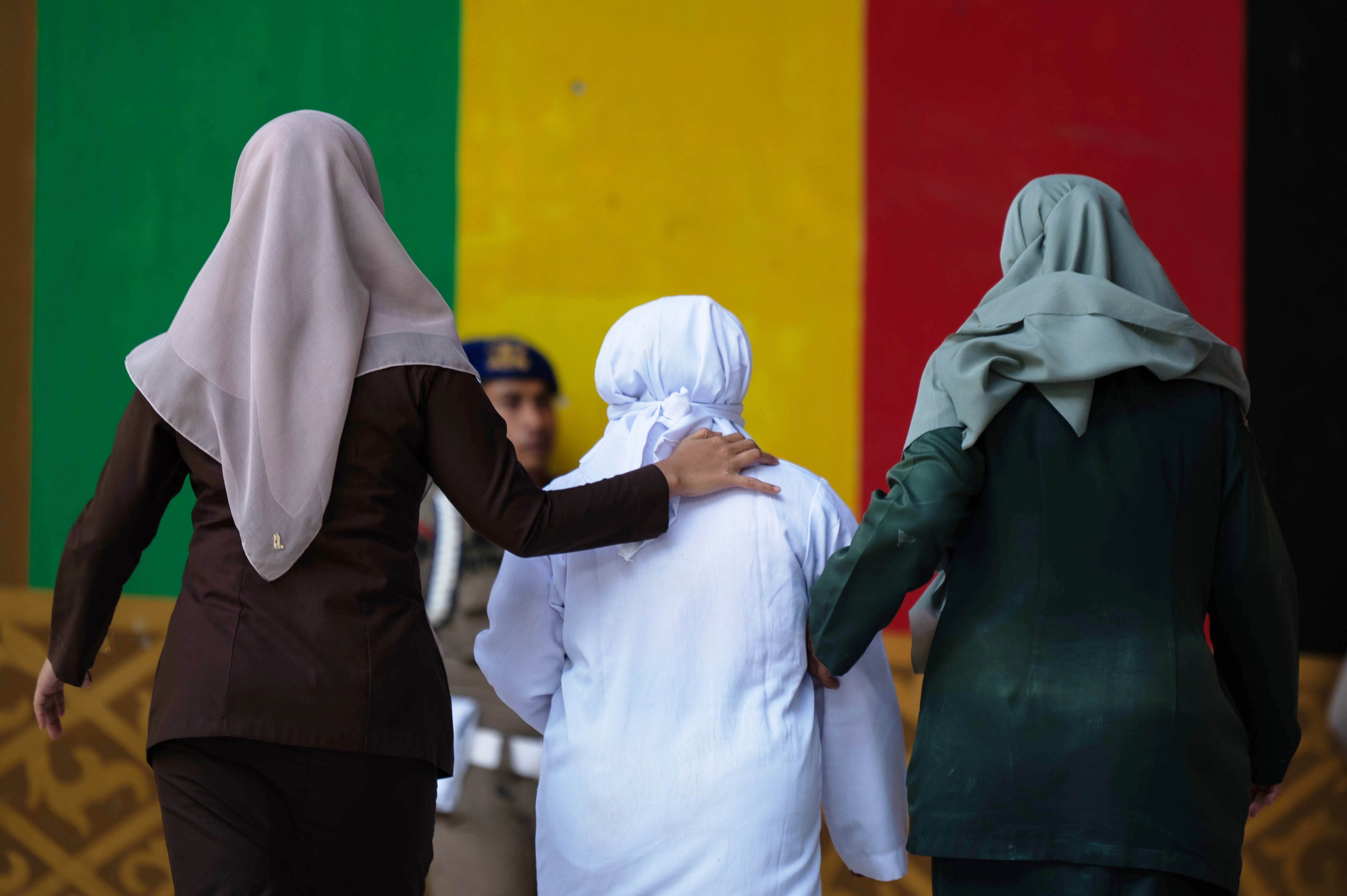Shariah law officials escort a woman convicted of violating Islamic law by kissing a man, both unmarried, during a TikTok livestream after her public caning, in Banda Aceh, Indonesia, Thursday, July 2, 2026. (AP Photo/Reza Saifullah)