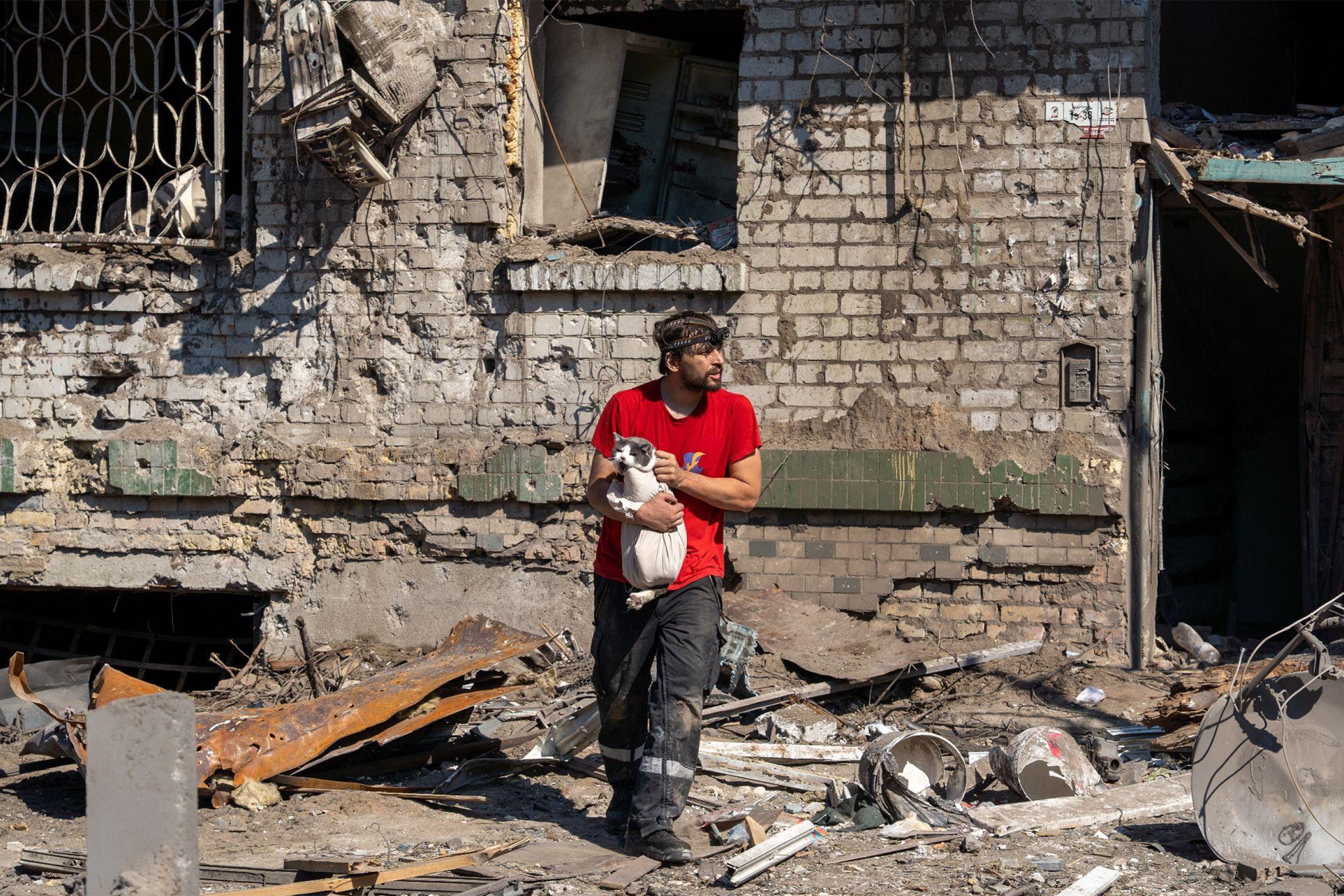 An animal rescuer rushes a cat out of a destroyed apartment block in Darnytsia, Kyiv