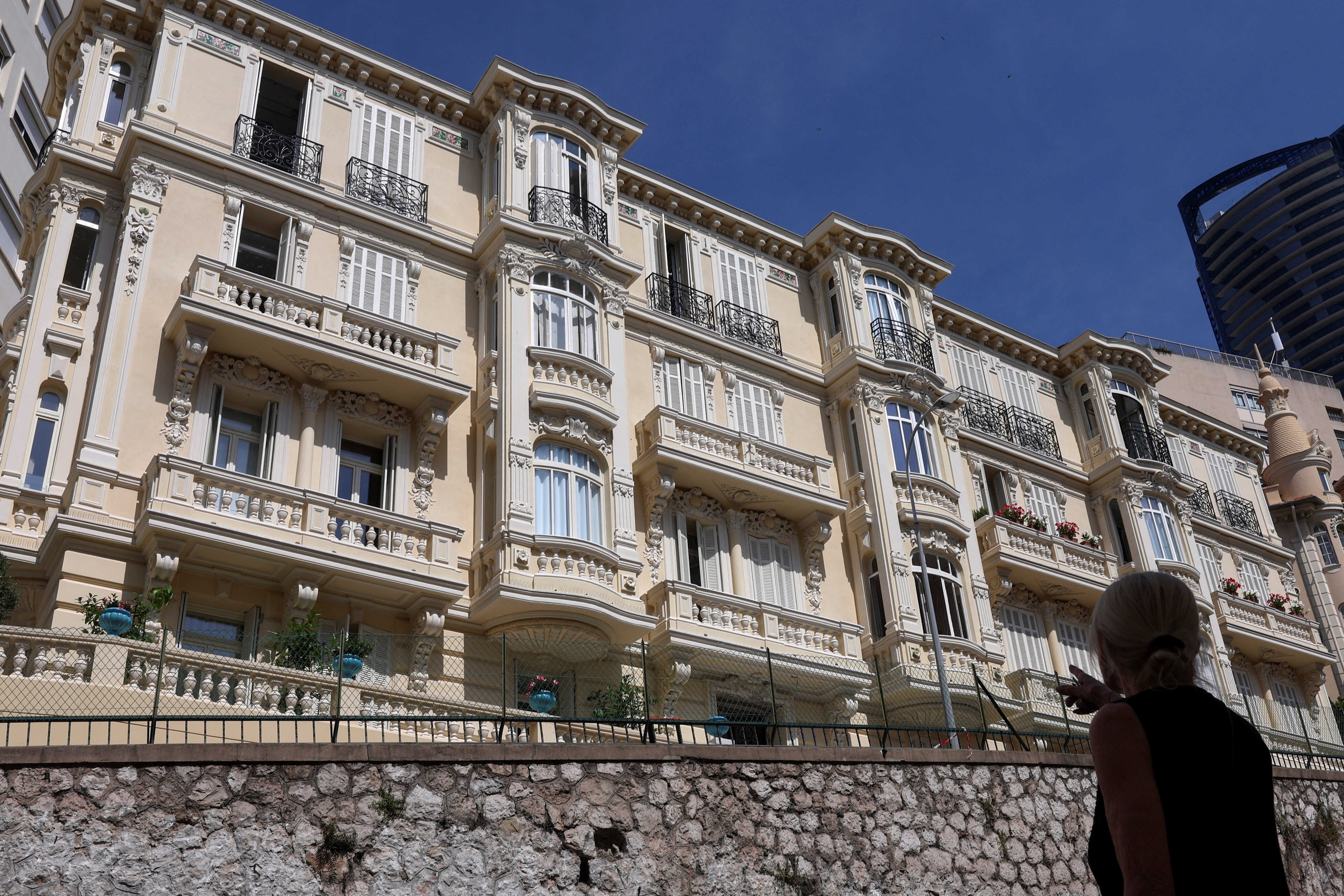 A woman points at a residential building, the site of an explosion that occurred on Monday