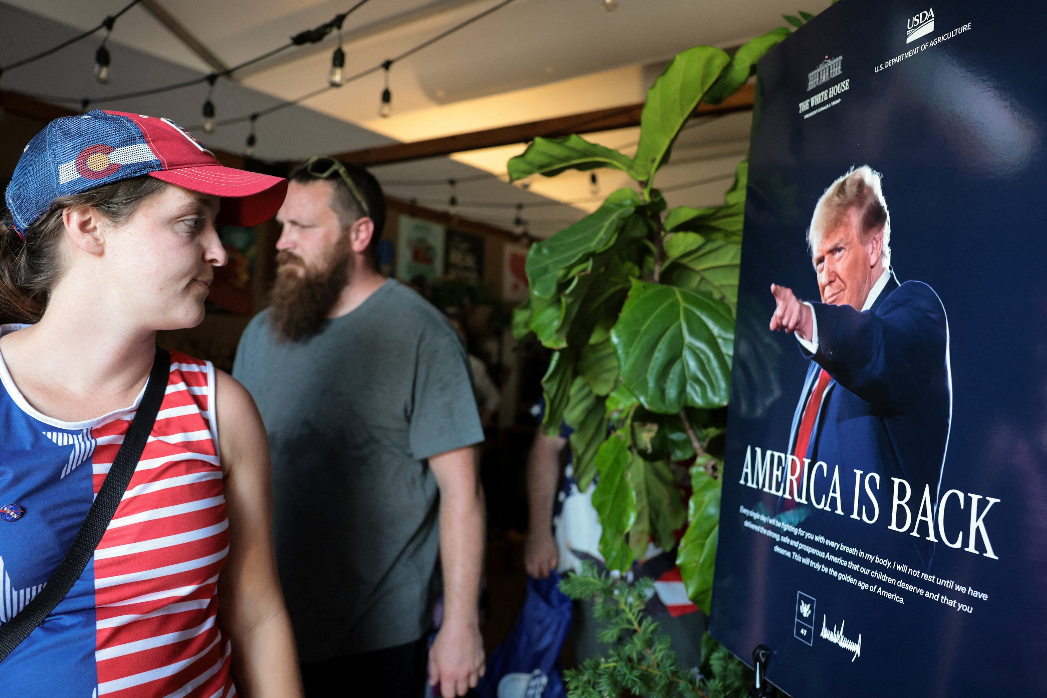 People are greeted by a poster of U.S. President Donald Trump at the U.S. Department of Agriculture (USDA) display at the Great American State Fair celebrating the 250th anniversary of U.S. independence in Washington.