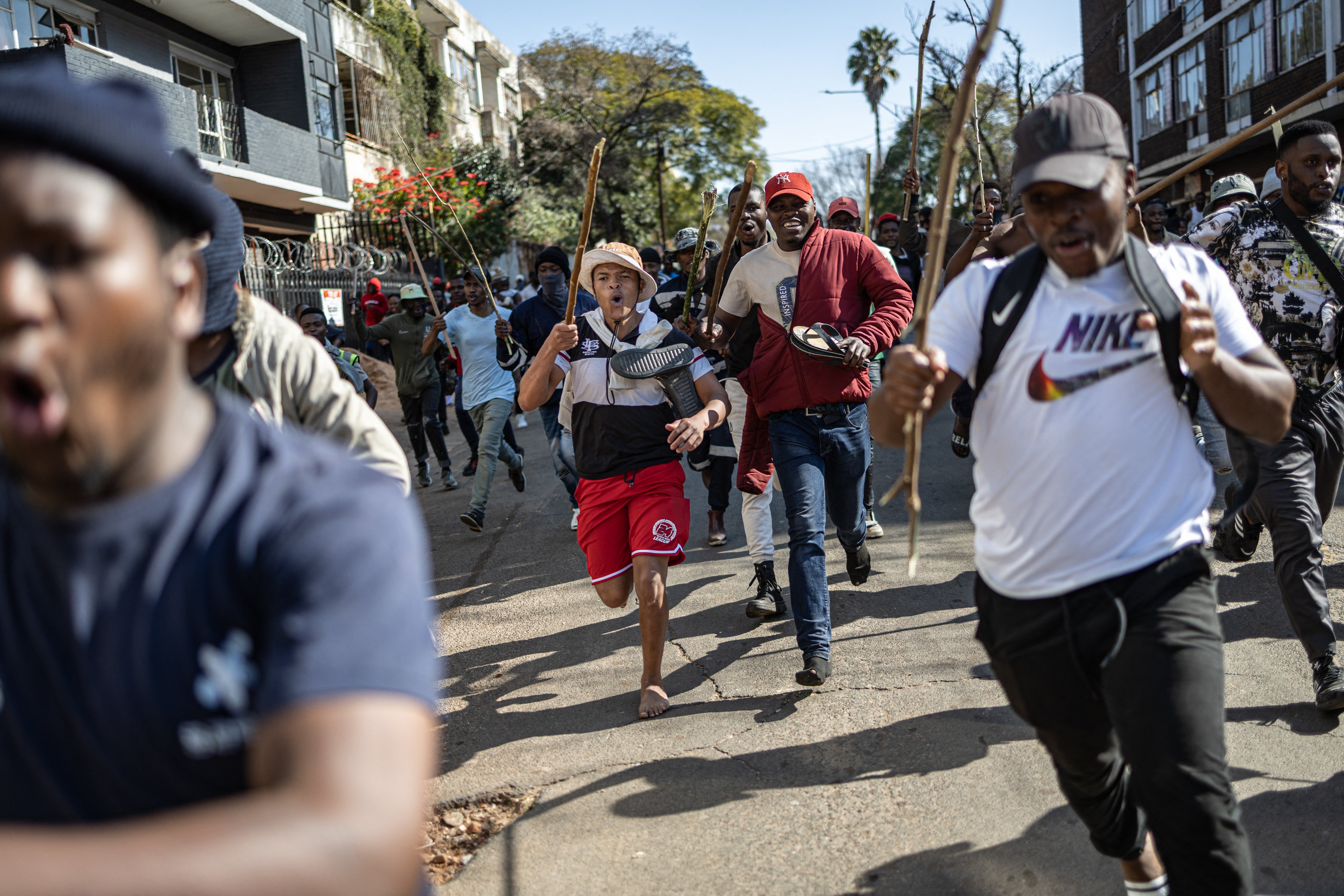 Protesters run after people they believe to be undocumented foreign nationals during a protest in Johannesburg