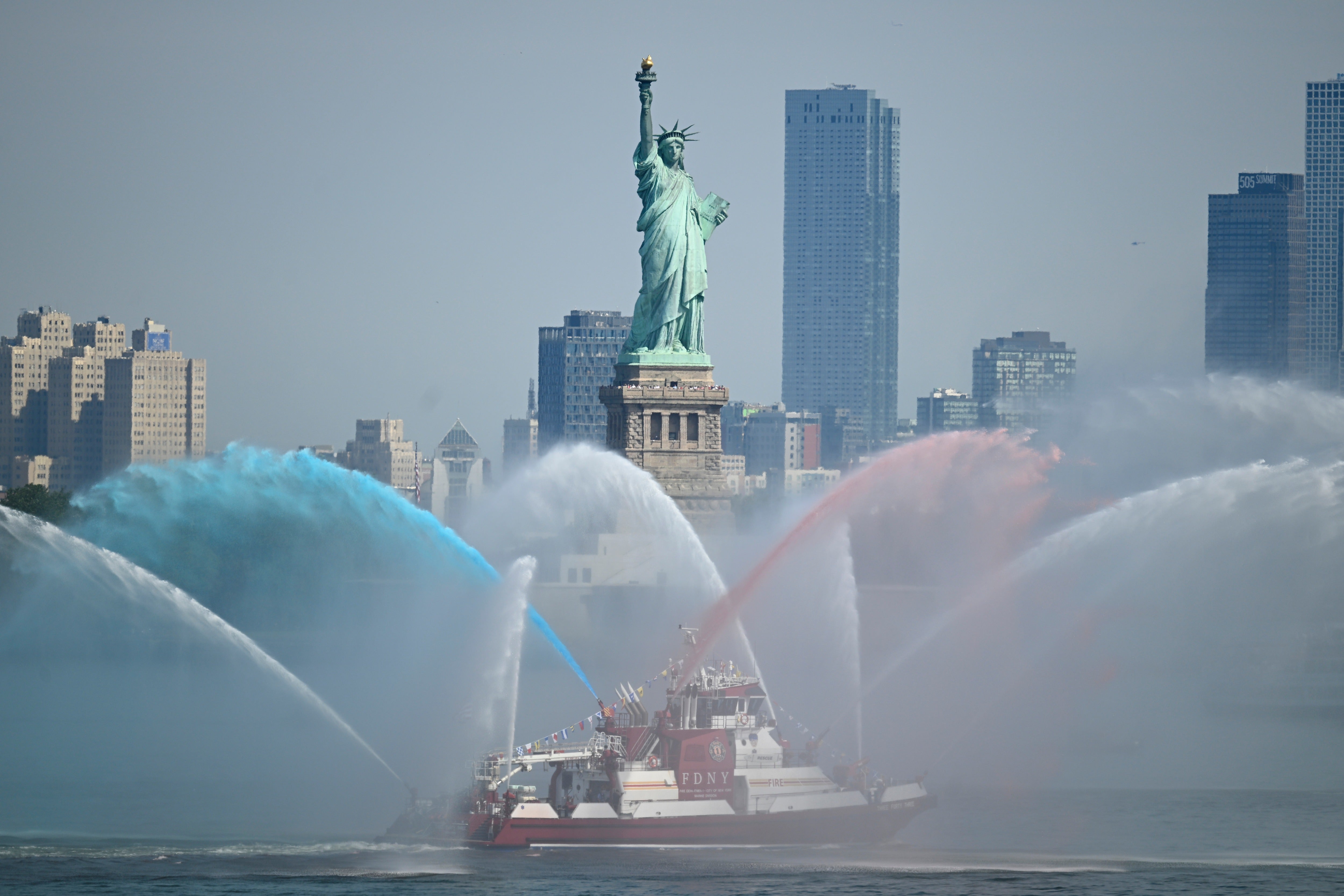 An FDNY boat sprays its hoses in tribute in front of the Statue of Liberty ahead of an international parade of tall sailing ships in New York Harbor on July 04, 2026 in New York City