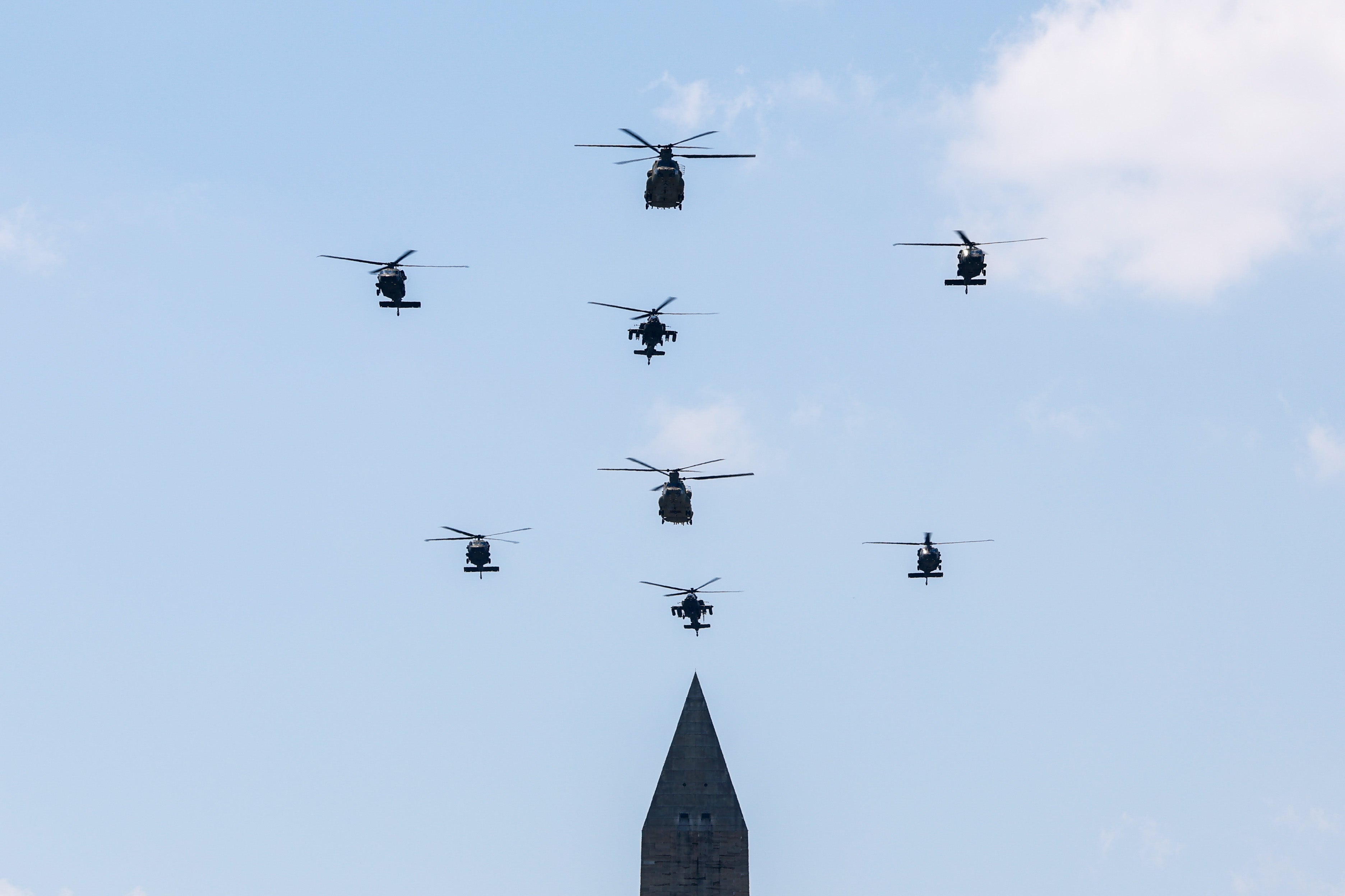 Military helicopters fly over the Washington Monument