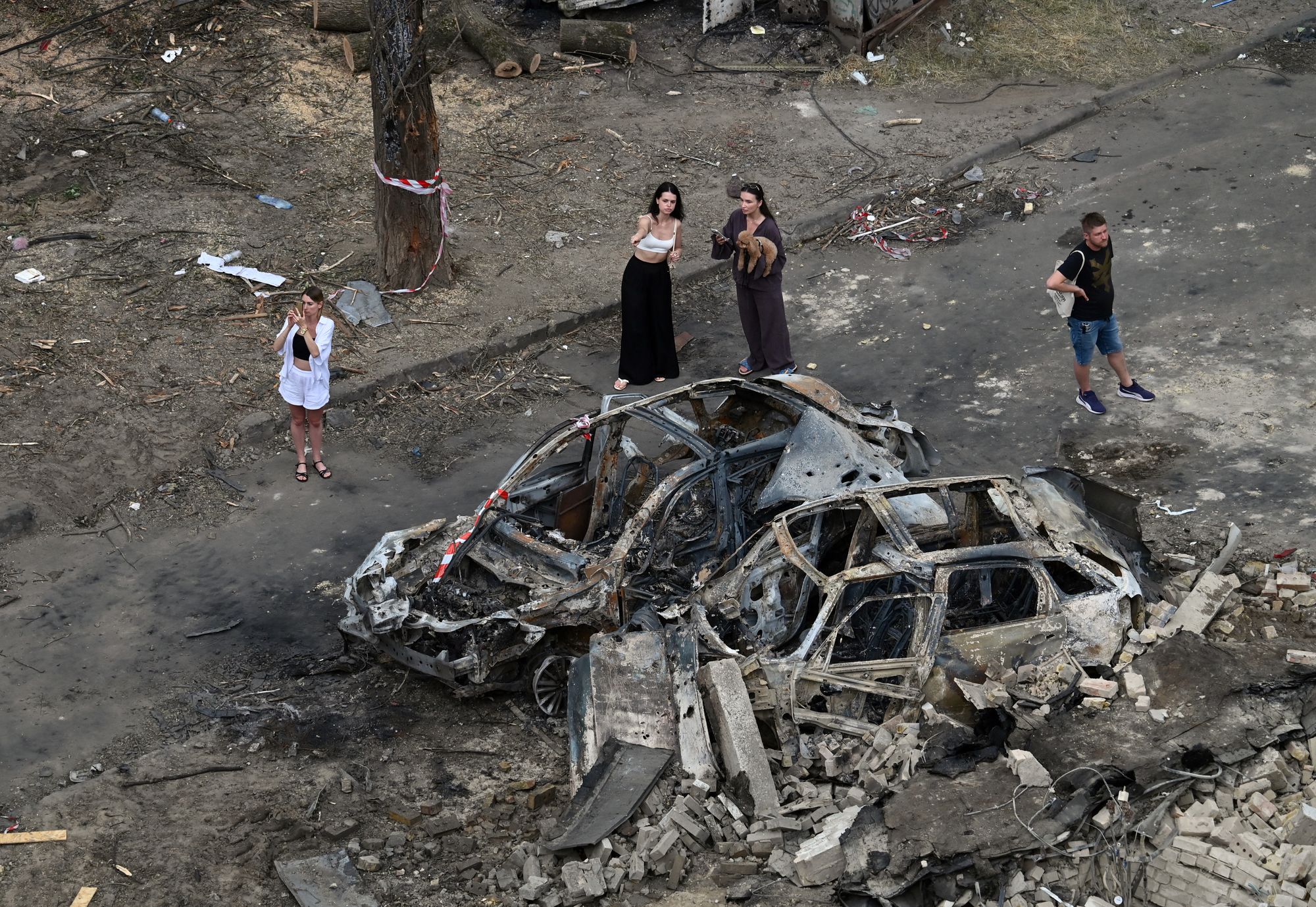 People examine burnt cars parked outside a residential building damaged following a Russian air attack on Kyiv