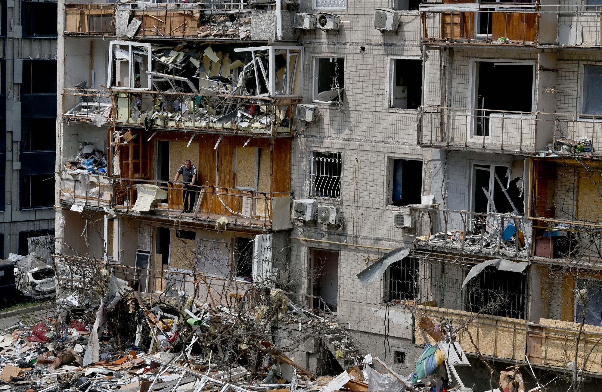 A local resident stands on the balcony of his flat in a residential building damaged by a Russian air attack Kyiv