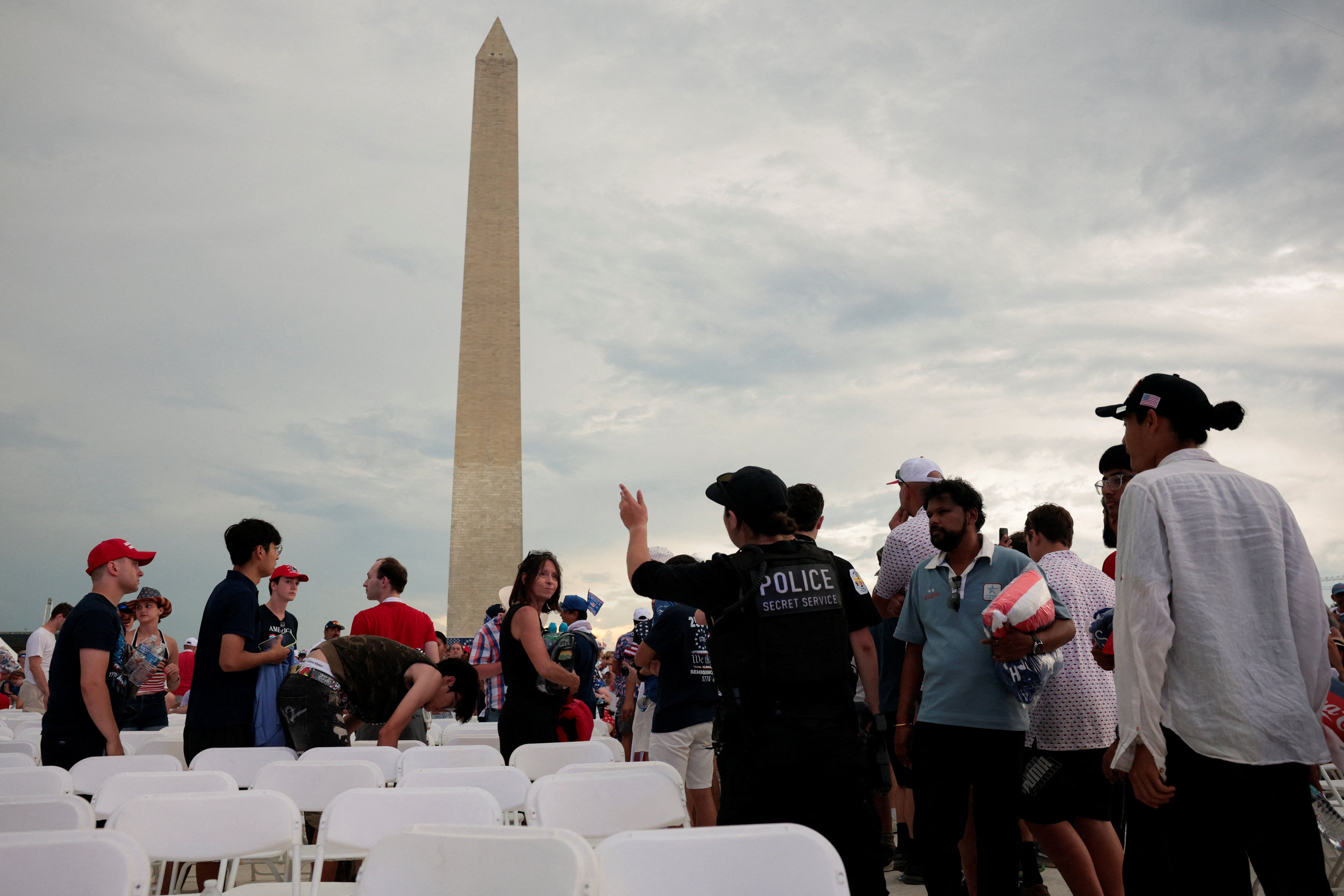 Freedom 250 attendees stand up from seats set up on the National Mall as officials order them to evacuate