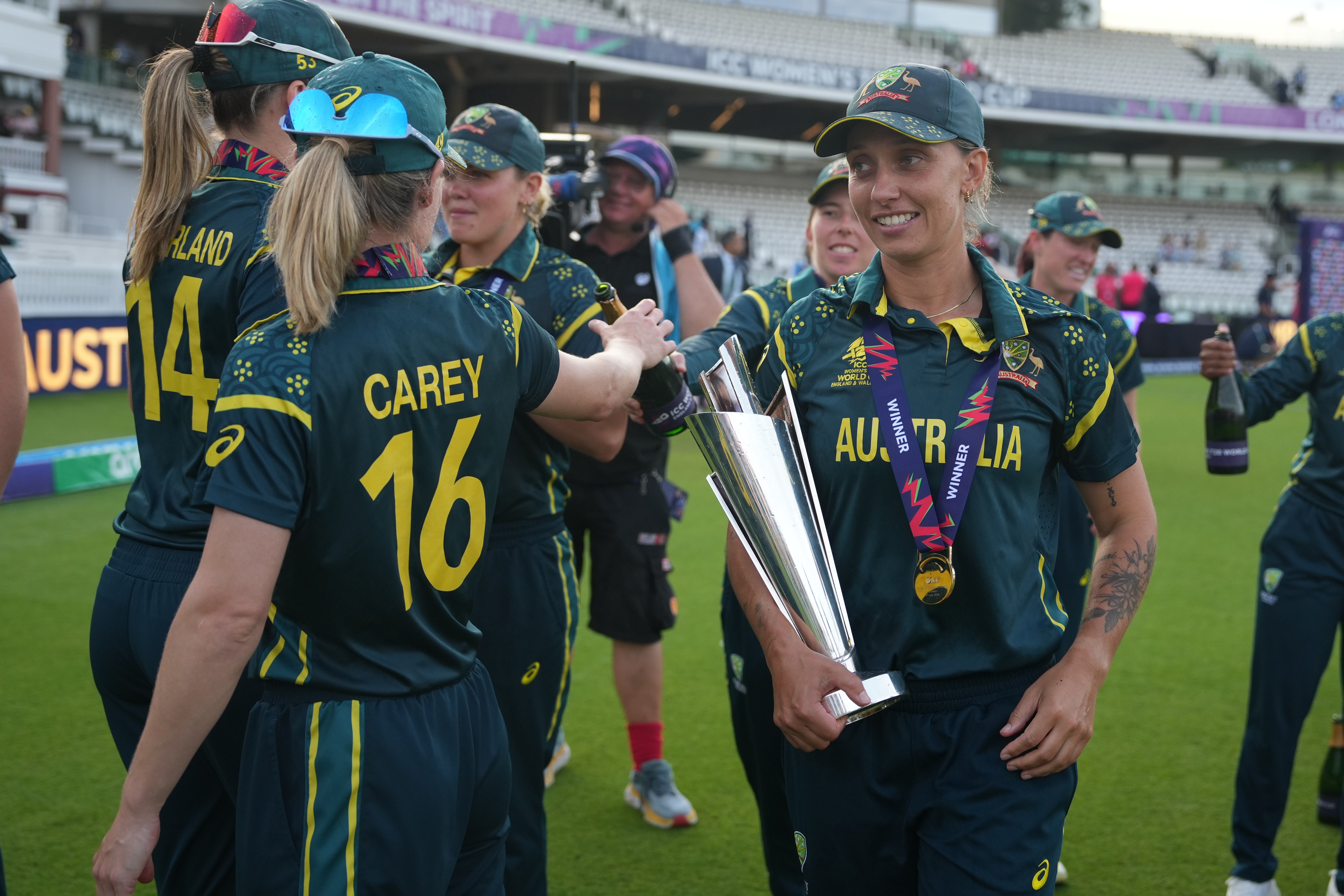 Australia's Ashleigh Gardner, carries the trophy as teammates celebrate