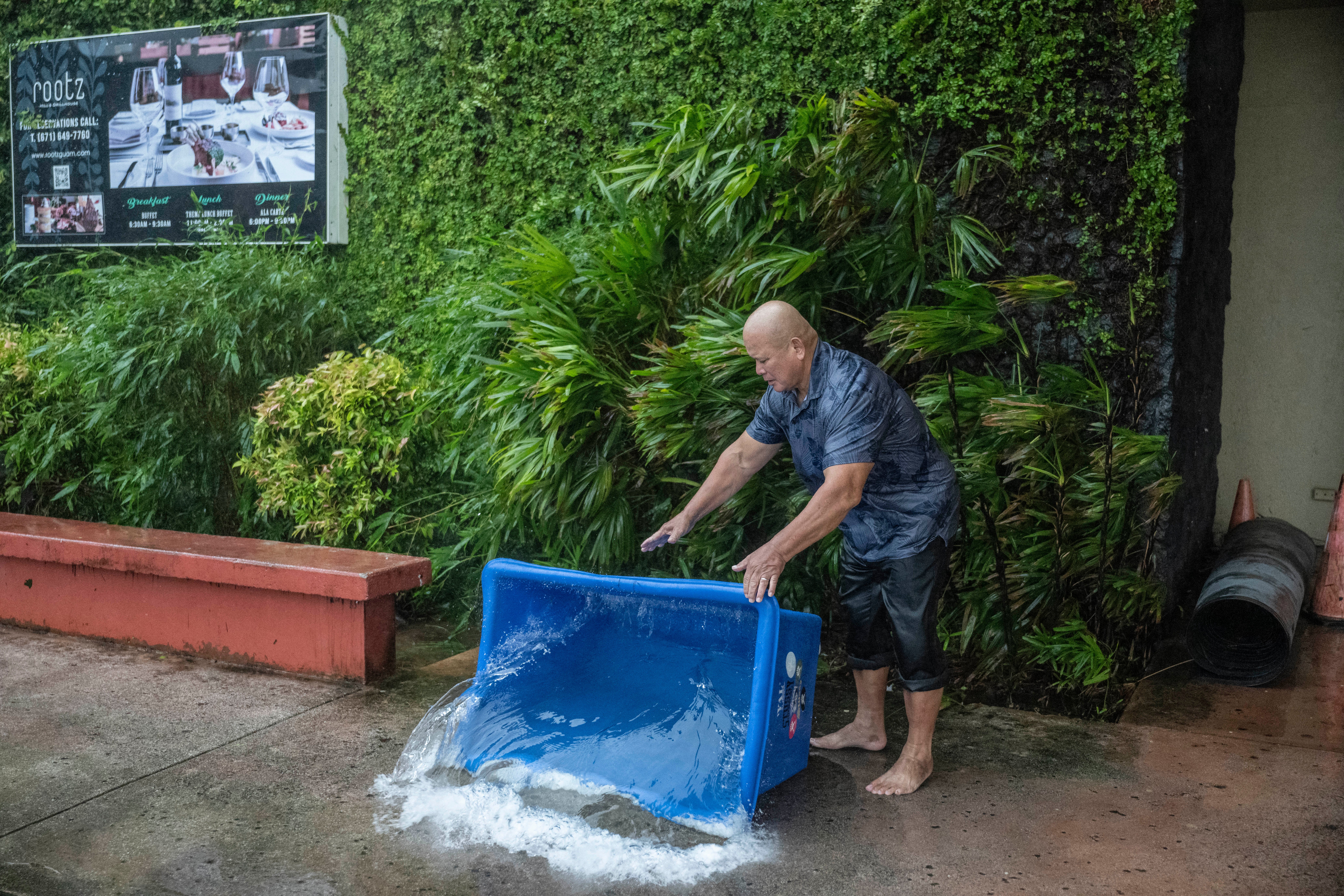 A hotel staff member removes water that leaked into a building during heavy rain brought by Super Typhoon Bavi in Guam