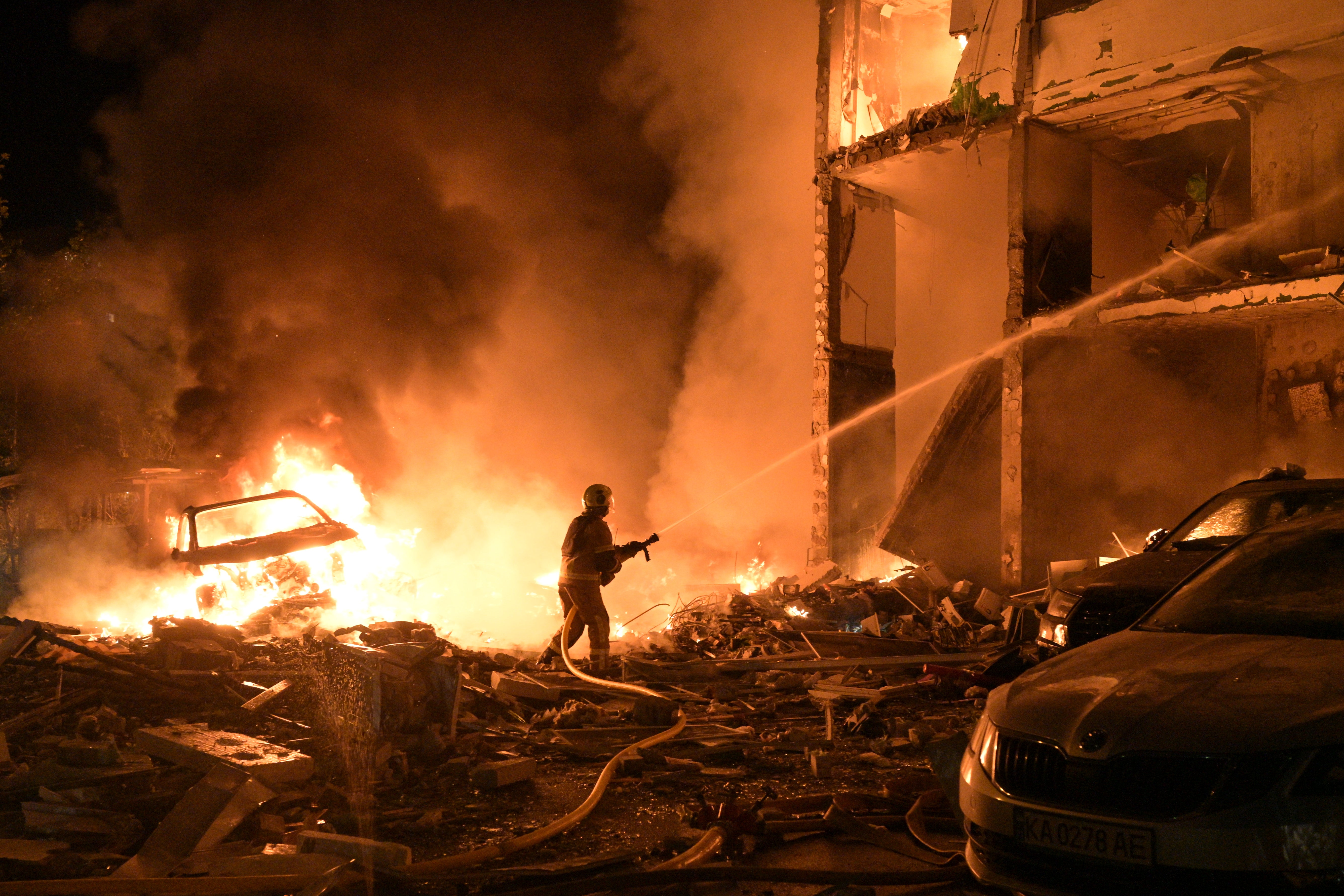 Emergency services personnel work to extinguish a fire following Russian missile attacks in Kyiv