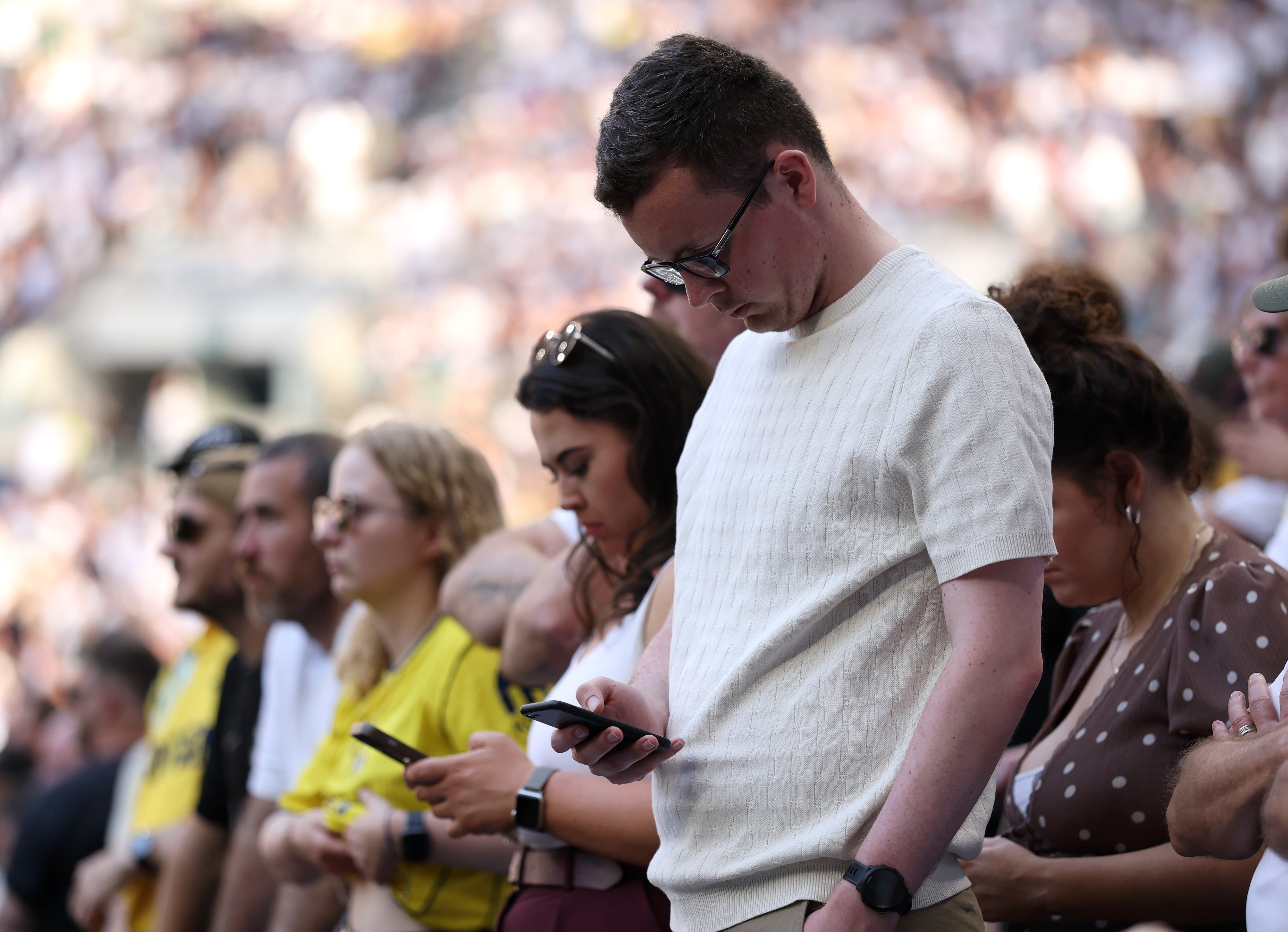 A soccer fan looks at his phone during a game last May in London, England. Tech neck can occur when looking at a smartphone, computer or other device