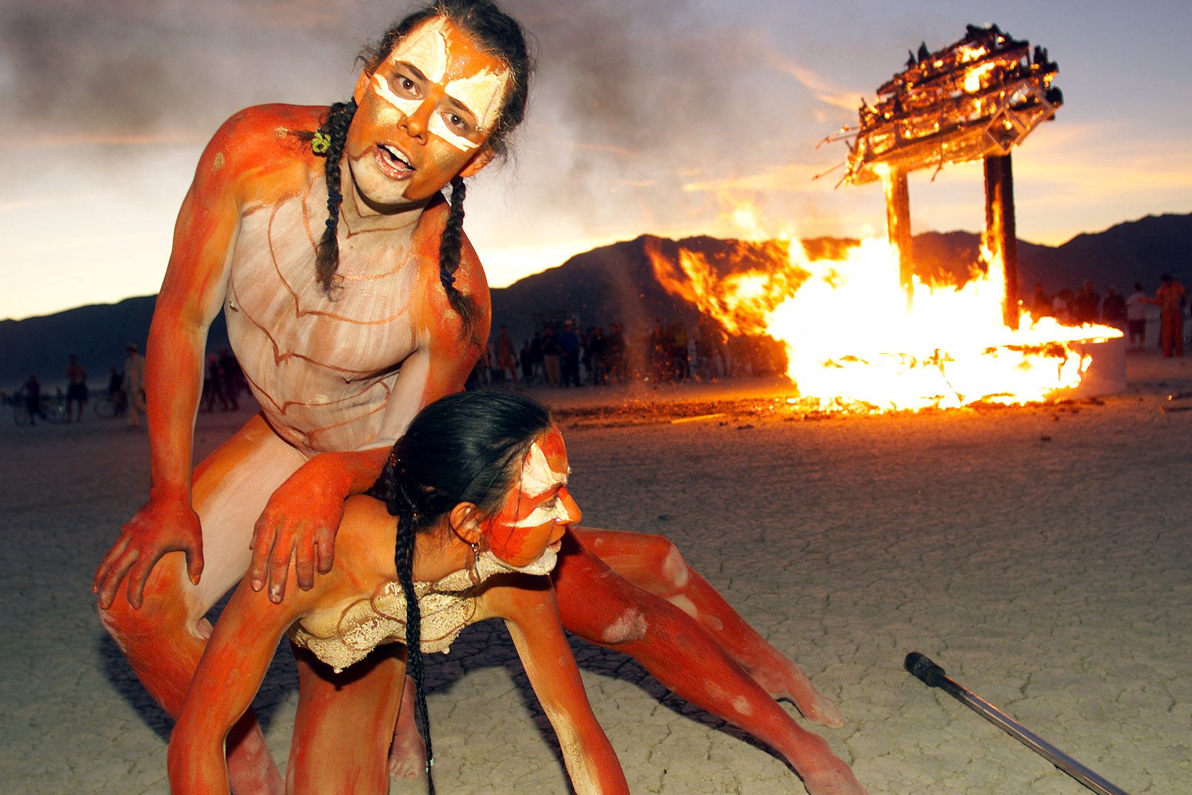 The artist Thomas Wood and a companion performing in front of a fire at Burning Man in 1999
