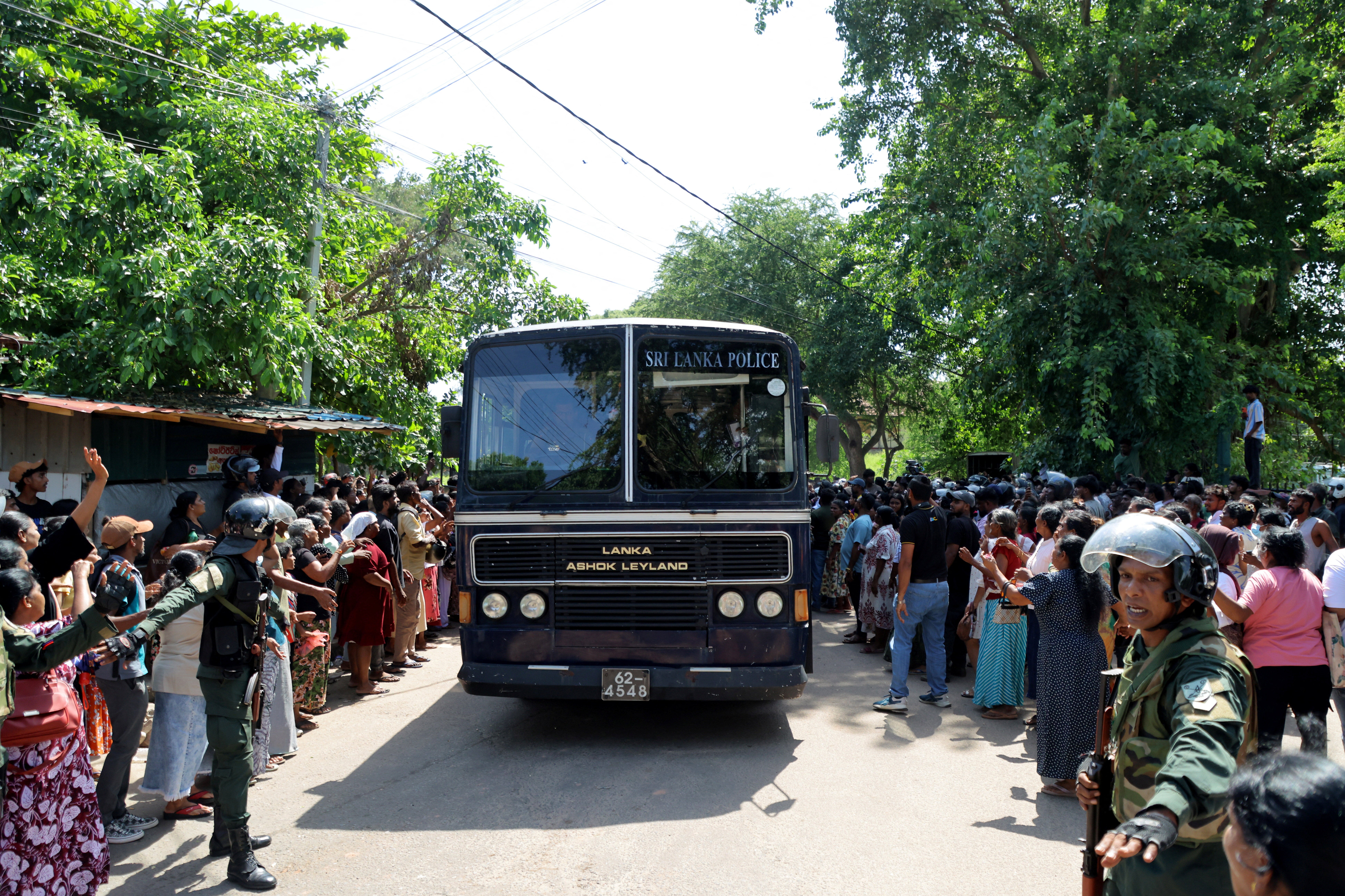 Members of security forces make way for a bus carrying prisoners to be transferred to another prison following clashes between two groups of inmates at Negombo Prison