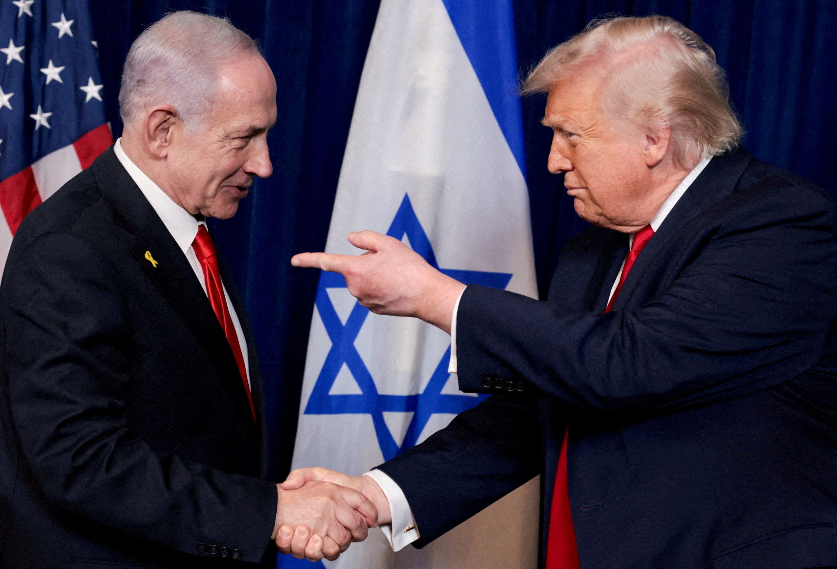 President Donald Trump points his finger towards Israeli Prime Minister Benjamin Netanyahu as they shake hands during a press conference after meeting at Trump’s Mar-a-Lago club in December 2025