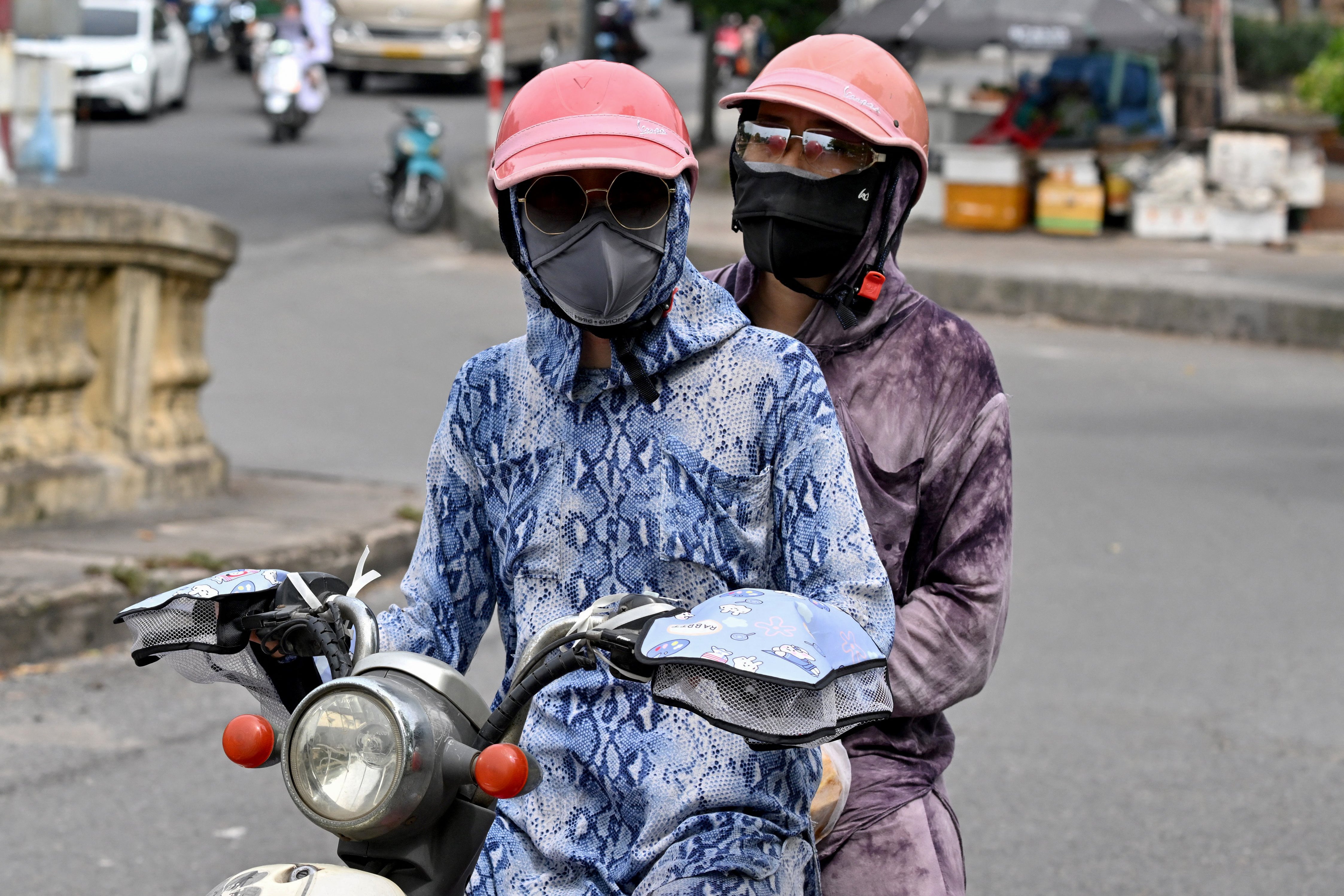 Motorcyclists cover up to avoid the heat in Hanoi