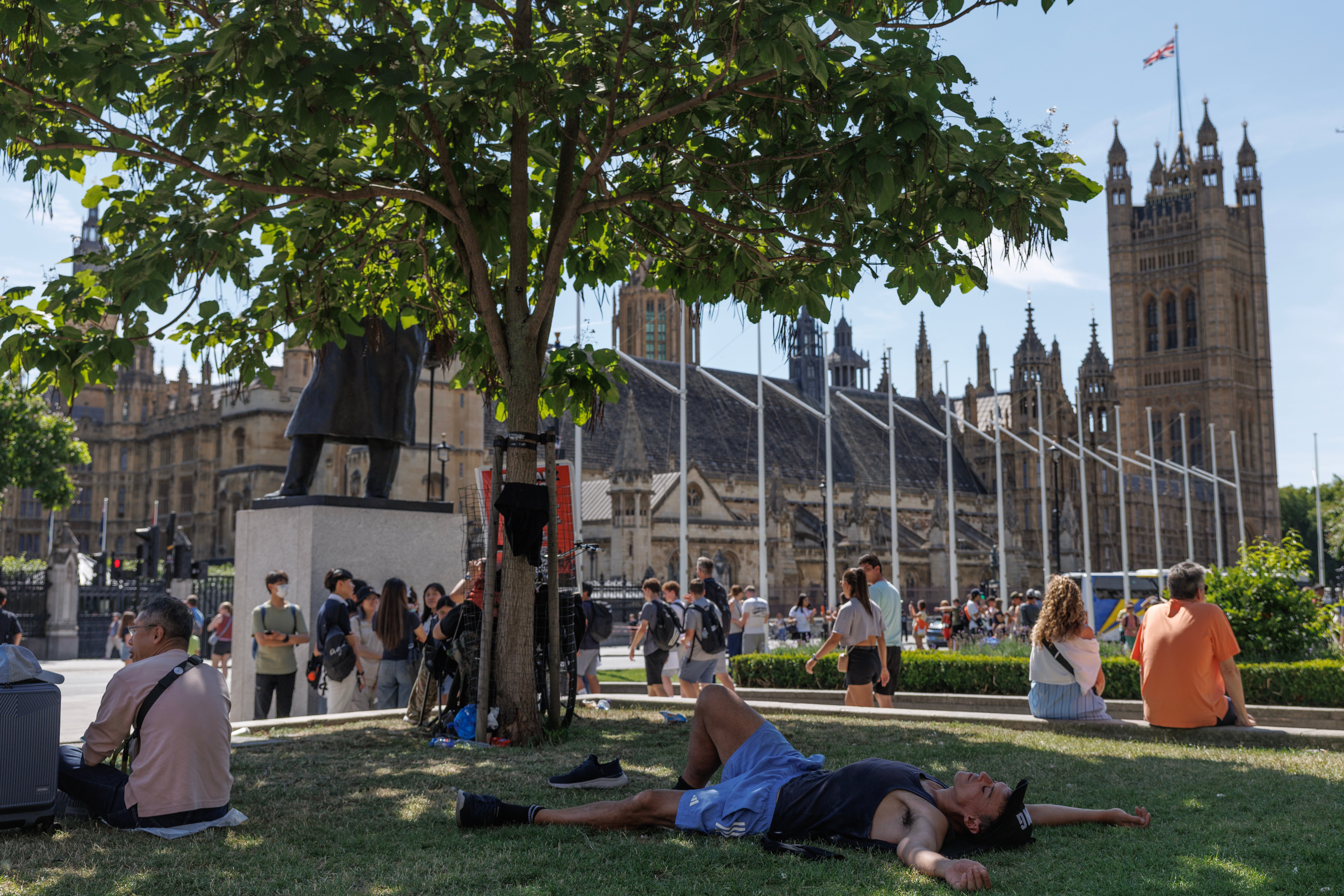 People relax in the shade in Parliament Square in London on July 6