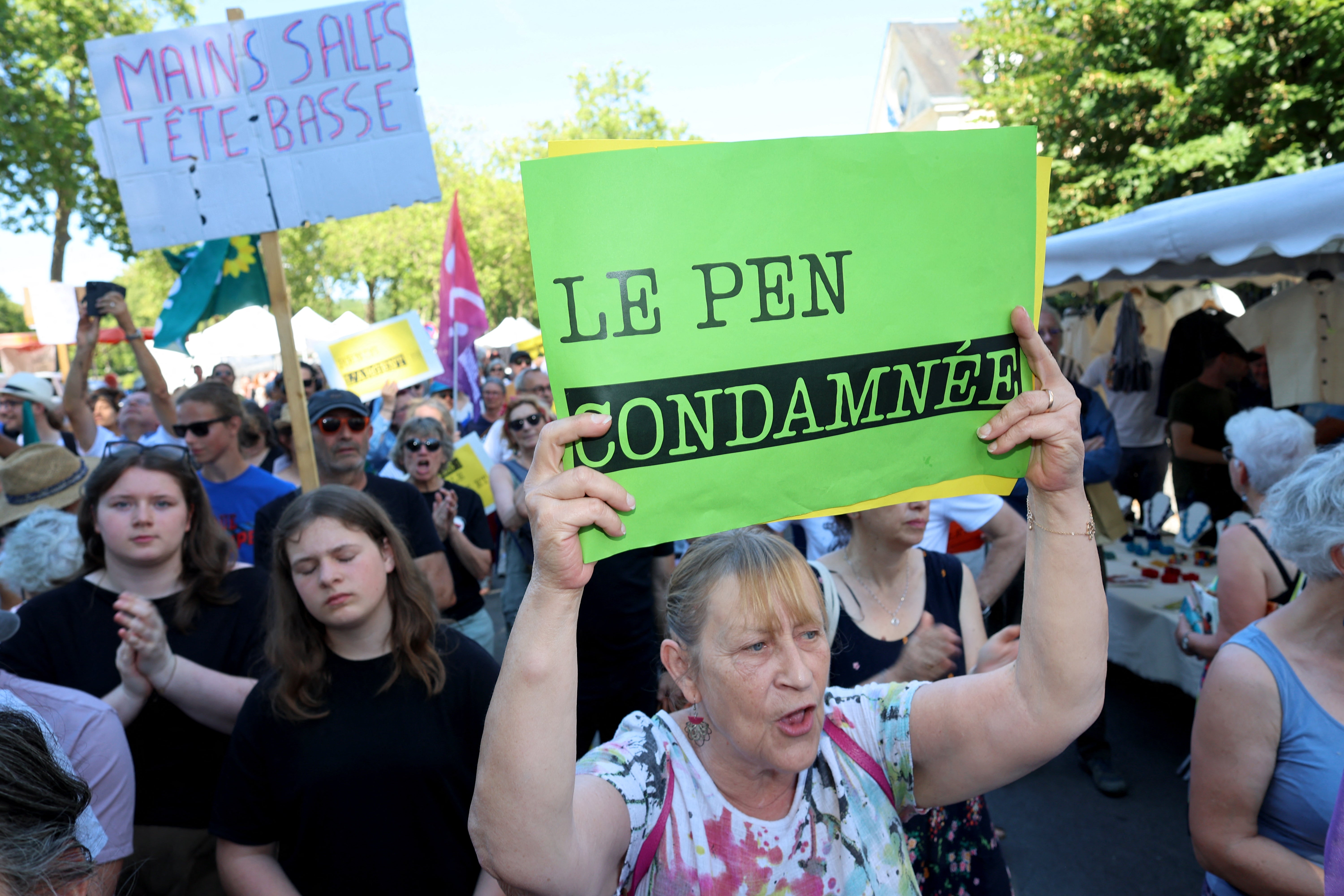 People hold placards against French far-right party Rassemblement National (RN) leader Marine Le Pen during a demonstration ahead of her planned visit.