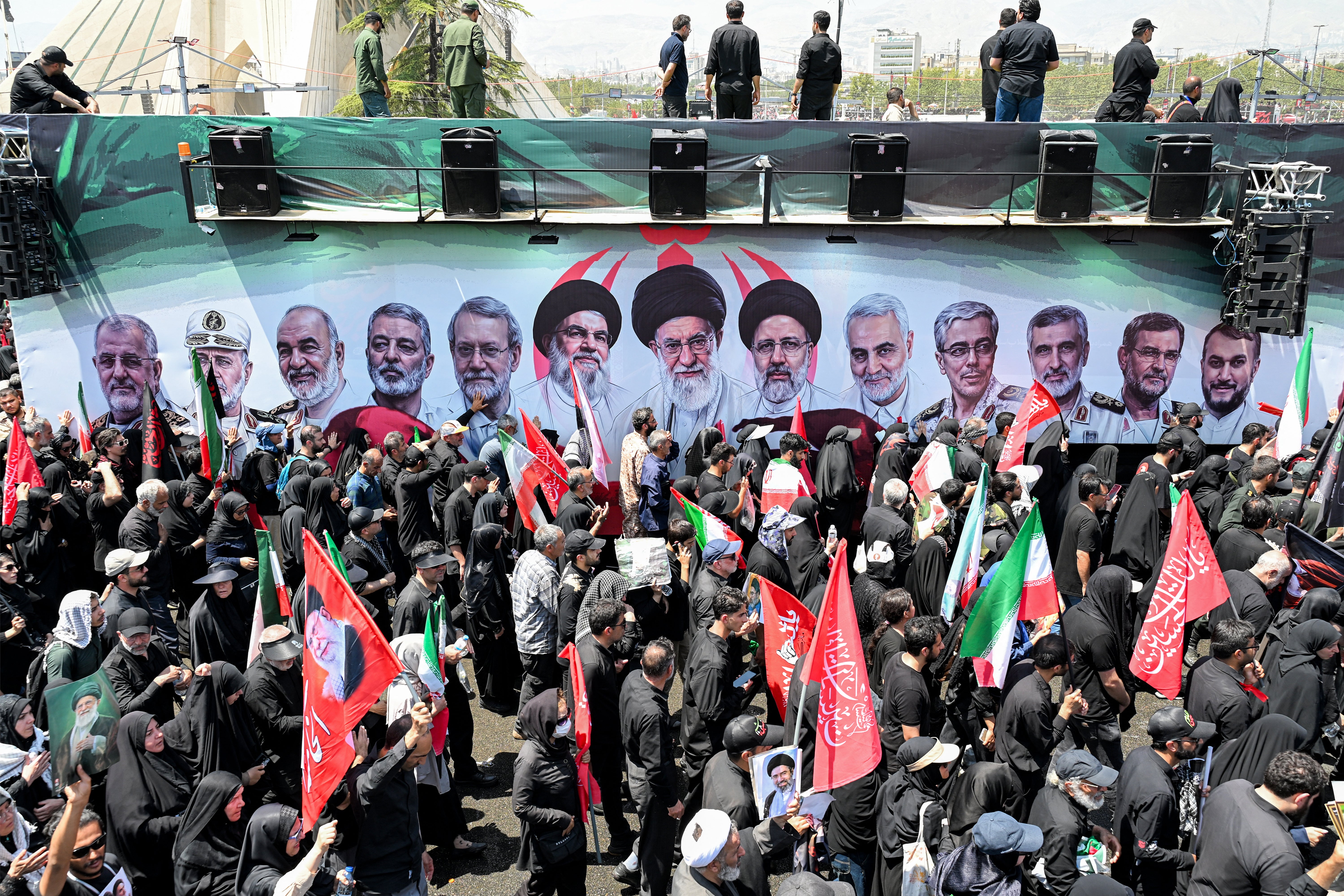 Mourners gather around one of the vehicles in the funeral procession for Iran's slain Supreme Leader Ali Khamenei at Azadi Square in Tehran on July 6, 2026