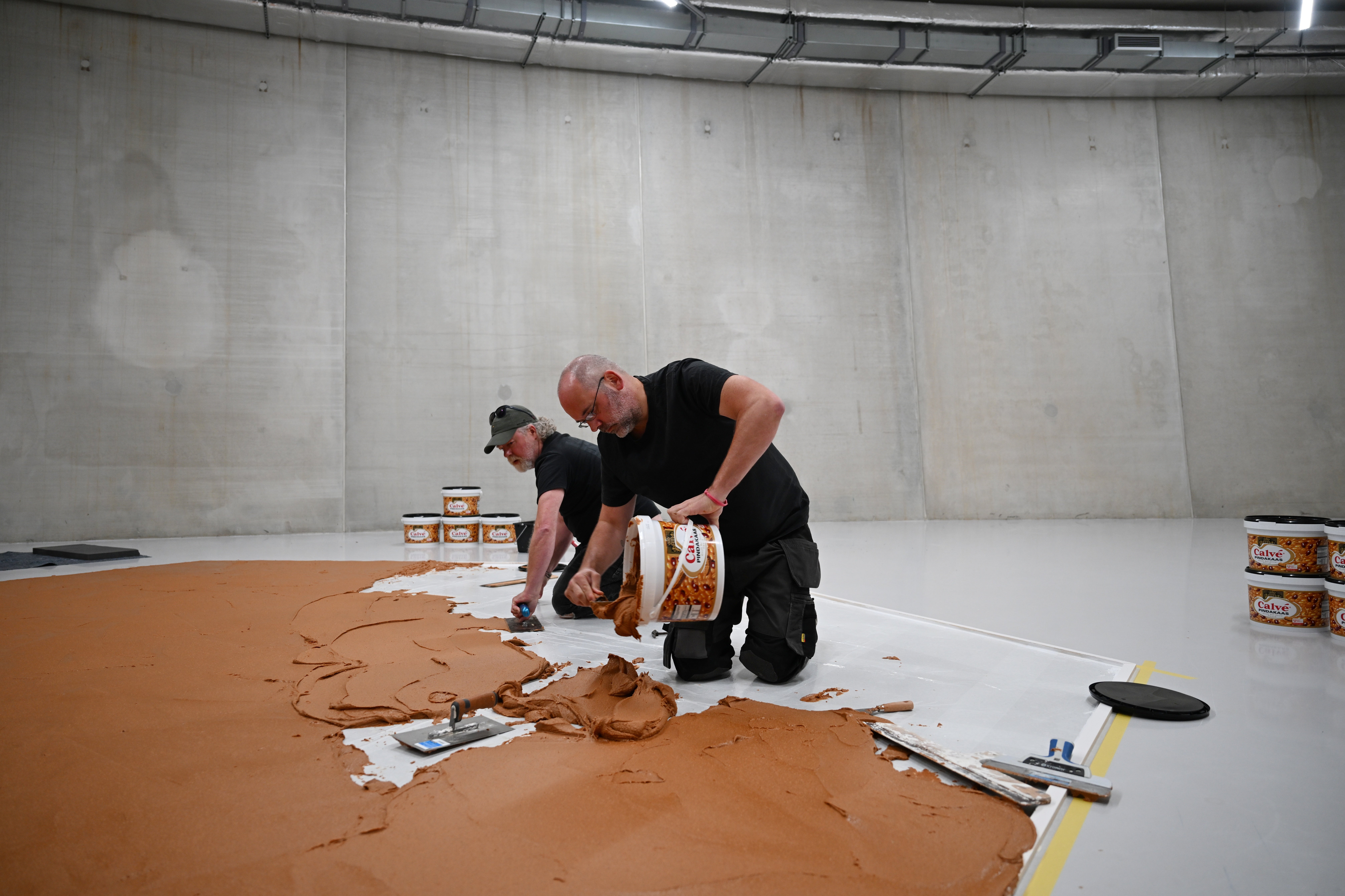 Workers spread peanut butter on a floor to recreate the ‘Peanut Butter Floor’ artwork in tribute to Dutch artist Wim T. Schippers at the Museum Boijmans Van Beuningen in Rotterdam, Netherlands, Friday, July 3, 2026