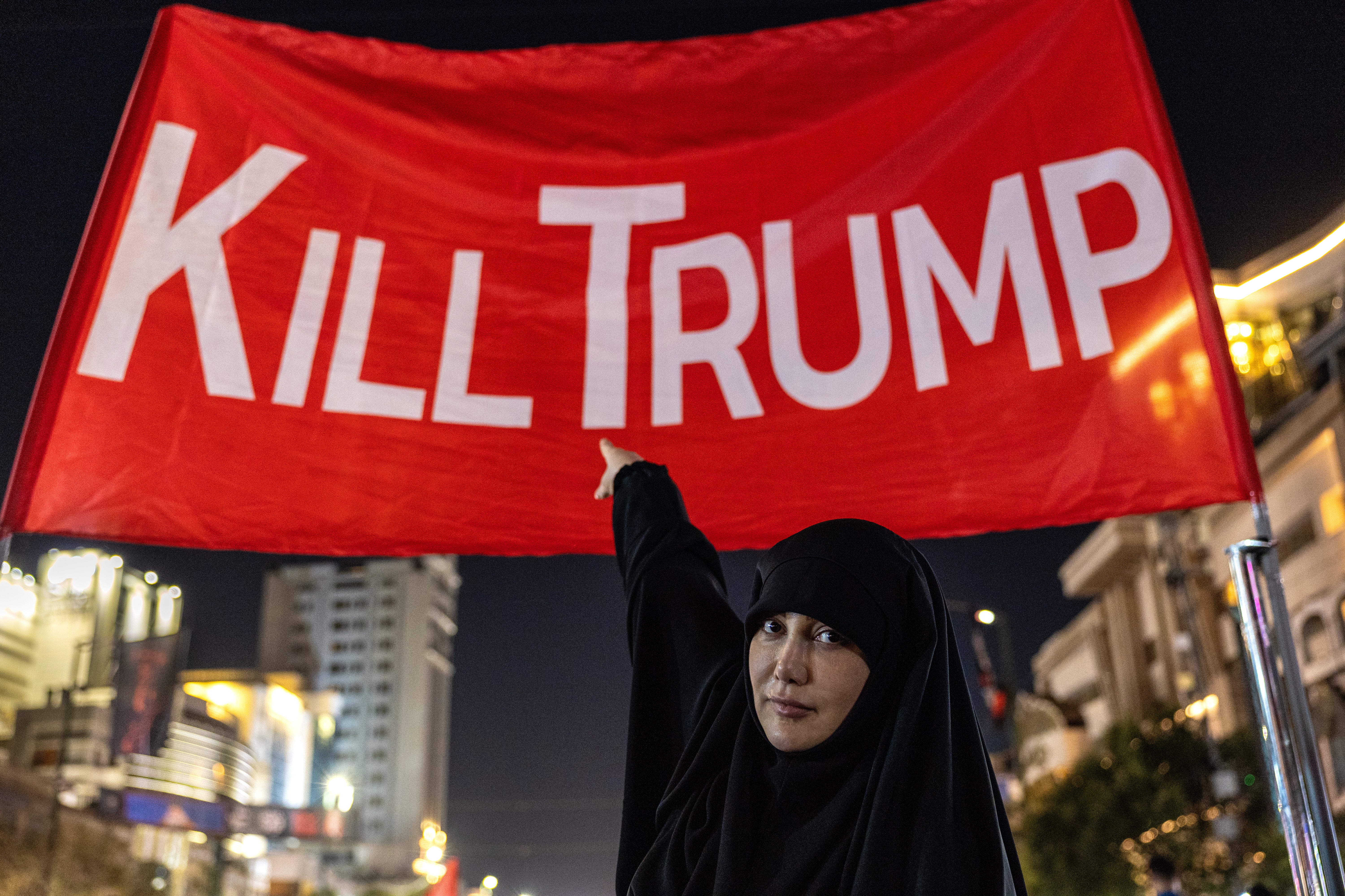 Mourners pose for photos under a banner set up in a main thoroughfare near the Imam Reza Shrine