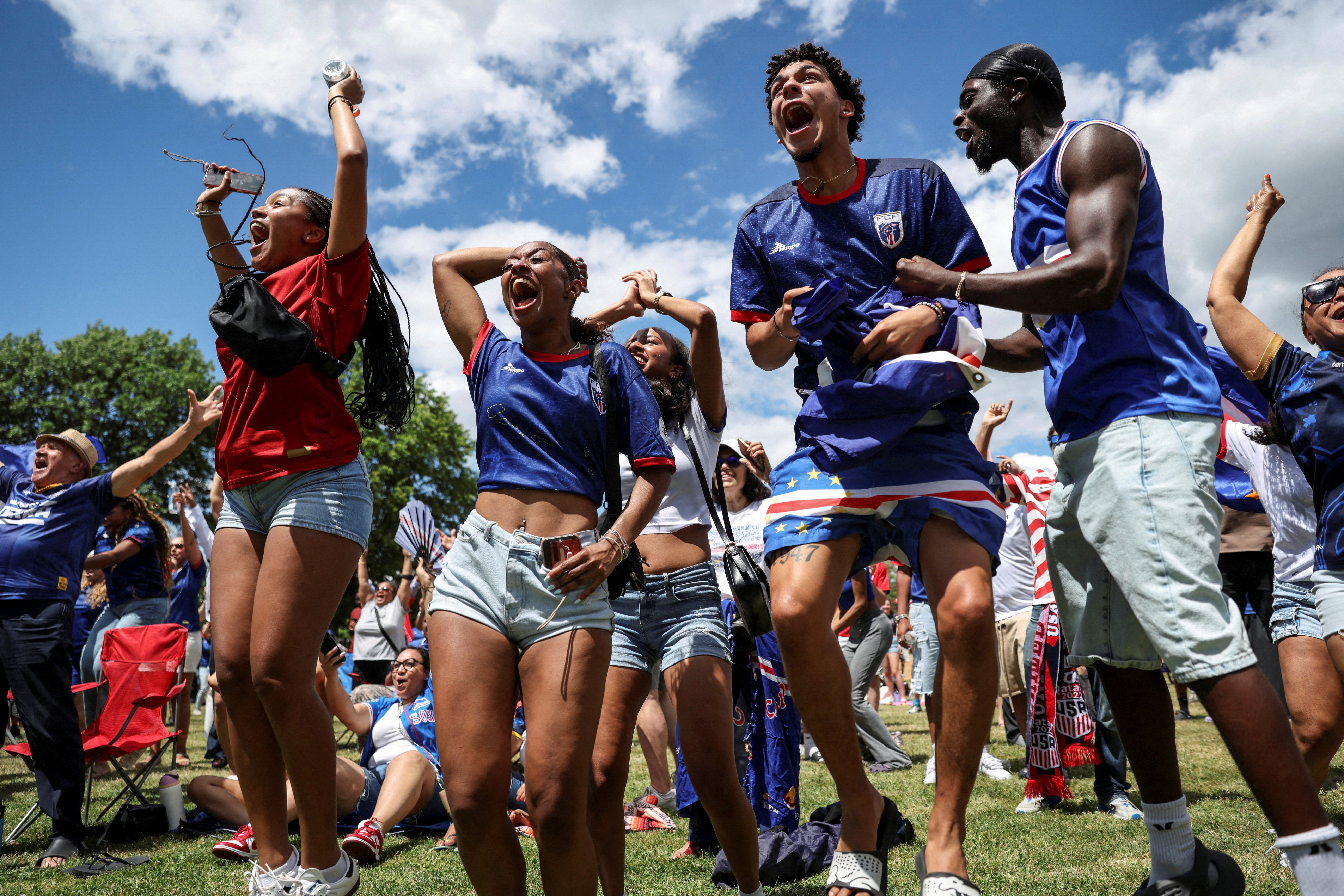 Cape Verde fans Ginaldo Verdieu, Alex Monteiro and Bruna Barbosa react as they watch the match on a screen at Town Field Park in Boston, Massachusetts