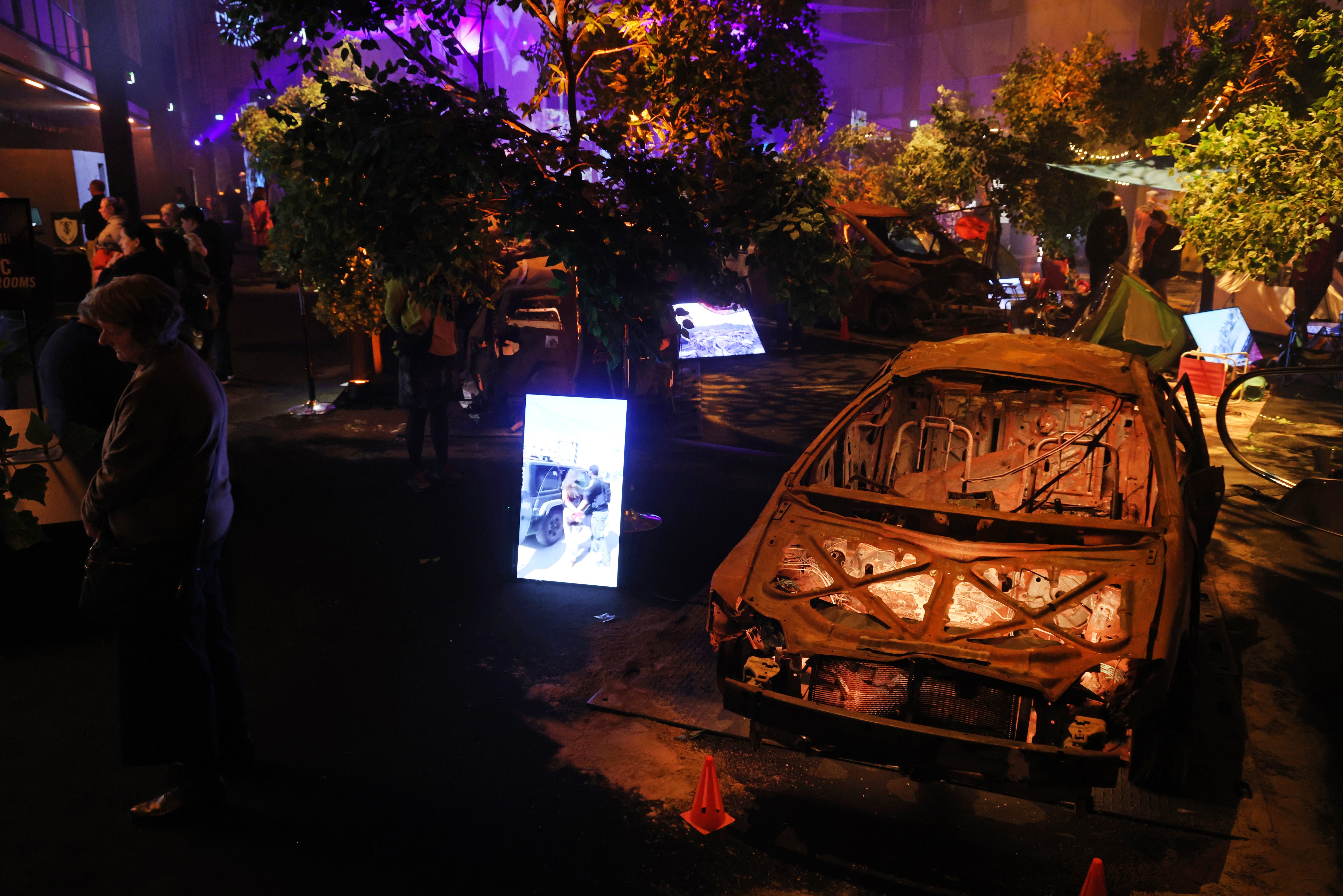 Visitors walk among burnt out cars and tents at the Nova Music Festival Exhibition in Berlin, Germany.