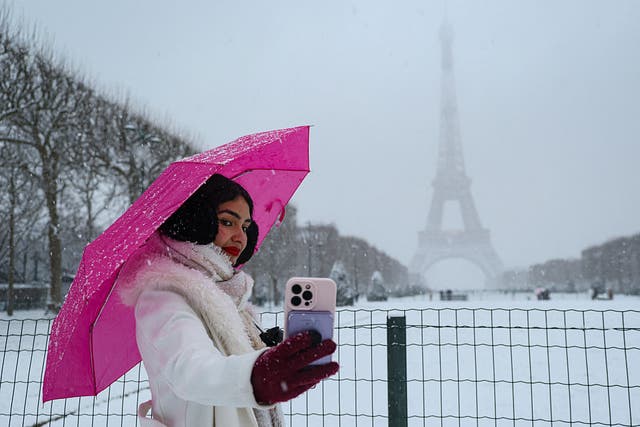 <p>Una mujer se toma una selfie en los Campos de Marte, cubiertos de nieve, cerca de la Torre Eiffel en París, el 5 de enero de 2026</p>