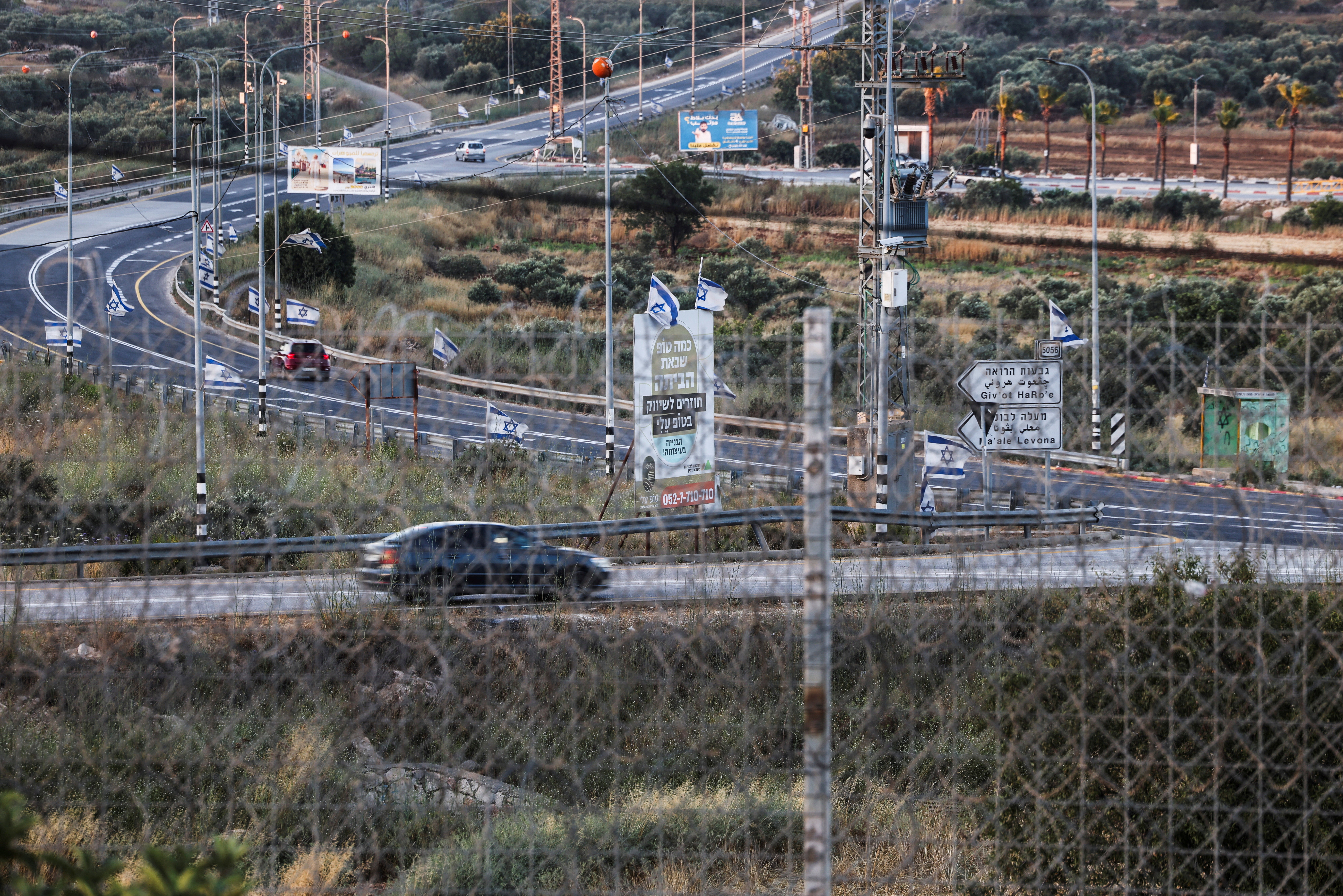 The road between Sinjil and Turmus Ayya, seen through the tall metal fencing installed by the Israeli military that closed off four of the five entrances to Sinjil, near Ramallah, in the Israeli-occupied West Bank, June 26, 2026