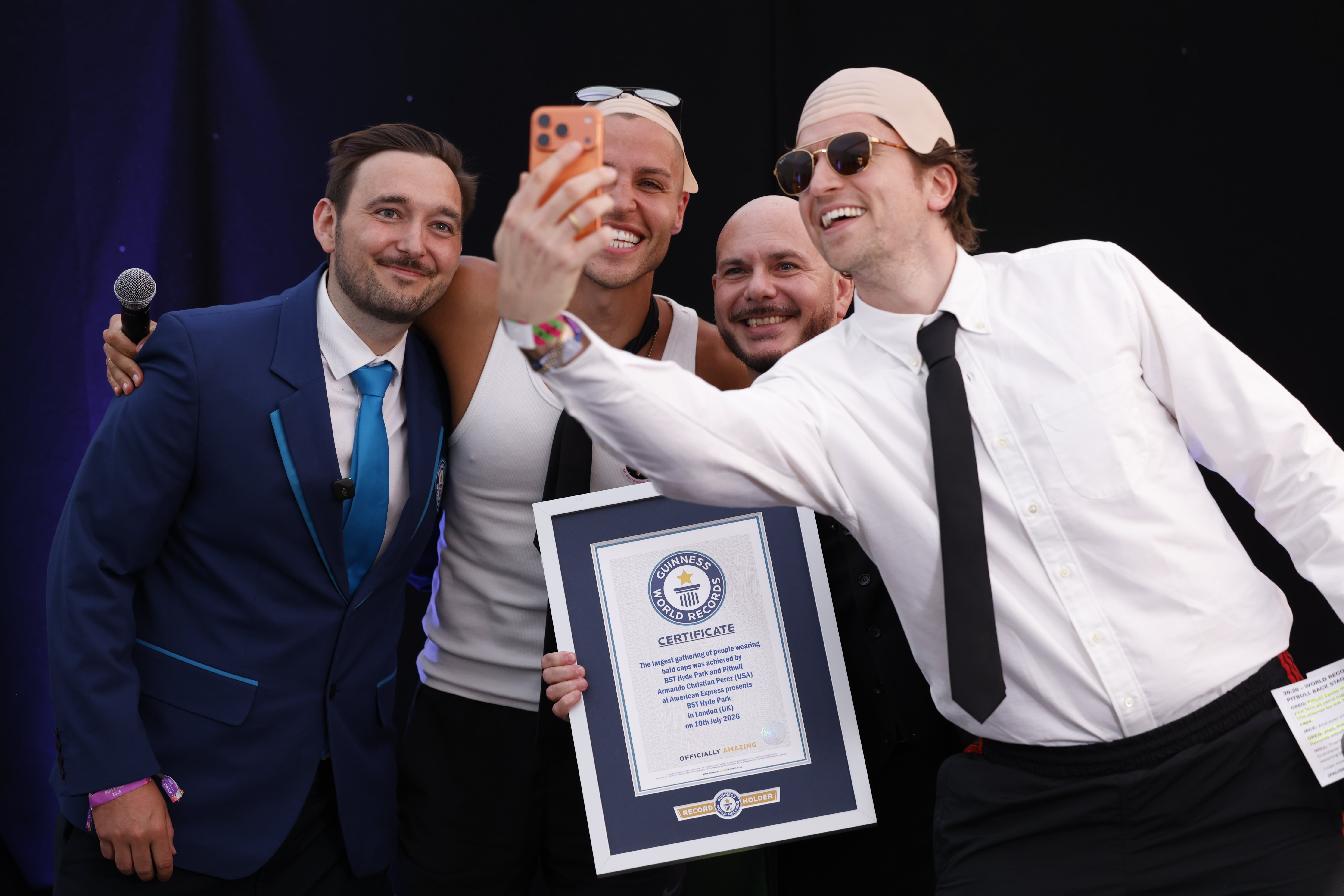 Greg James takes a photo of Pitbull, Jack Remmington and Will Munford after the rapper was presented with a Guinness World Record certificate (David Parry/PA)