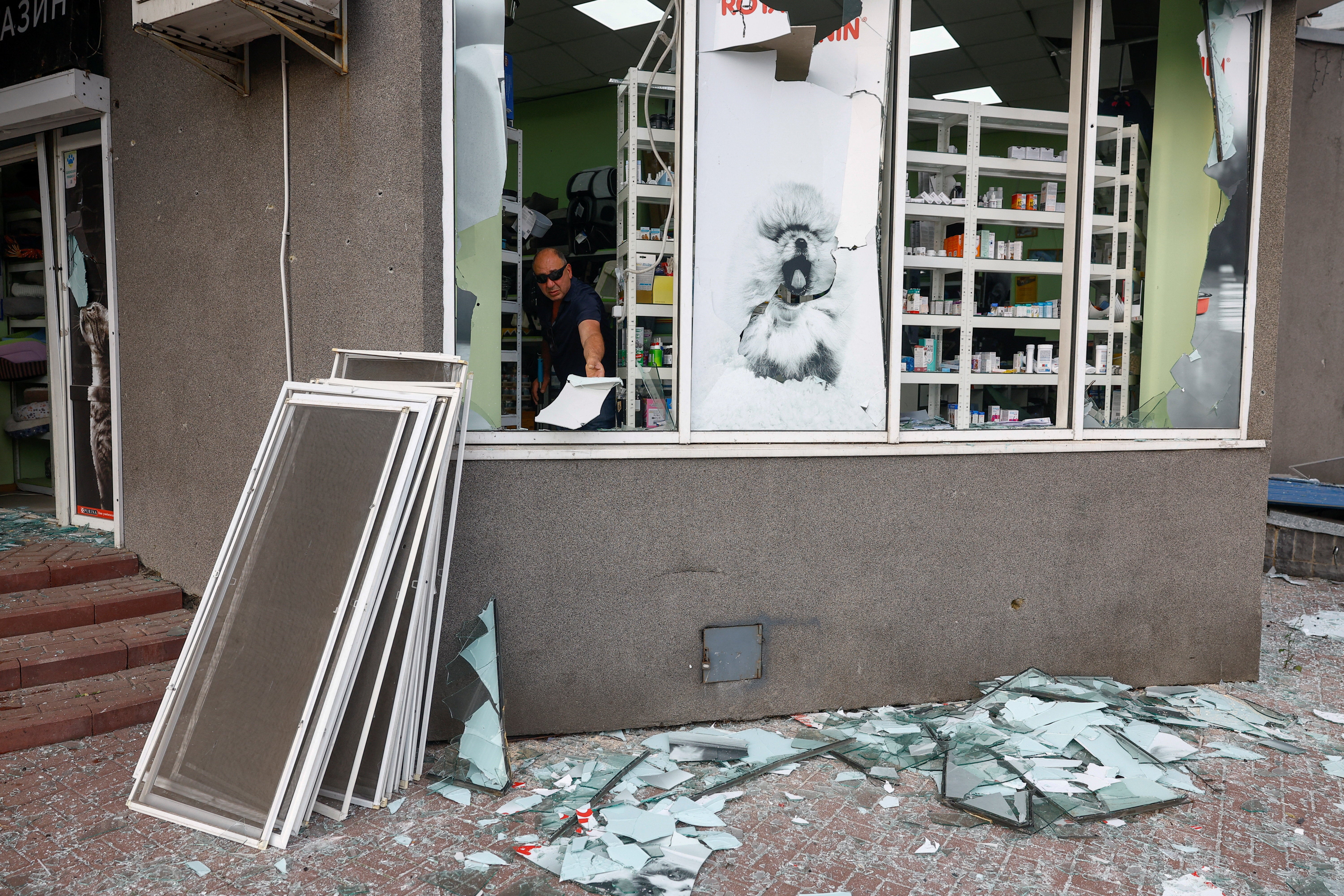 A resident removes debris from his pet shop, which was damaged during Russian missile strikes