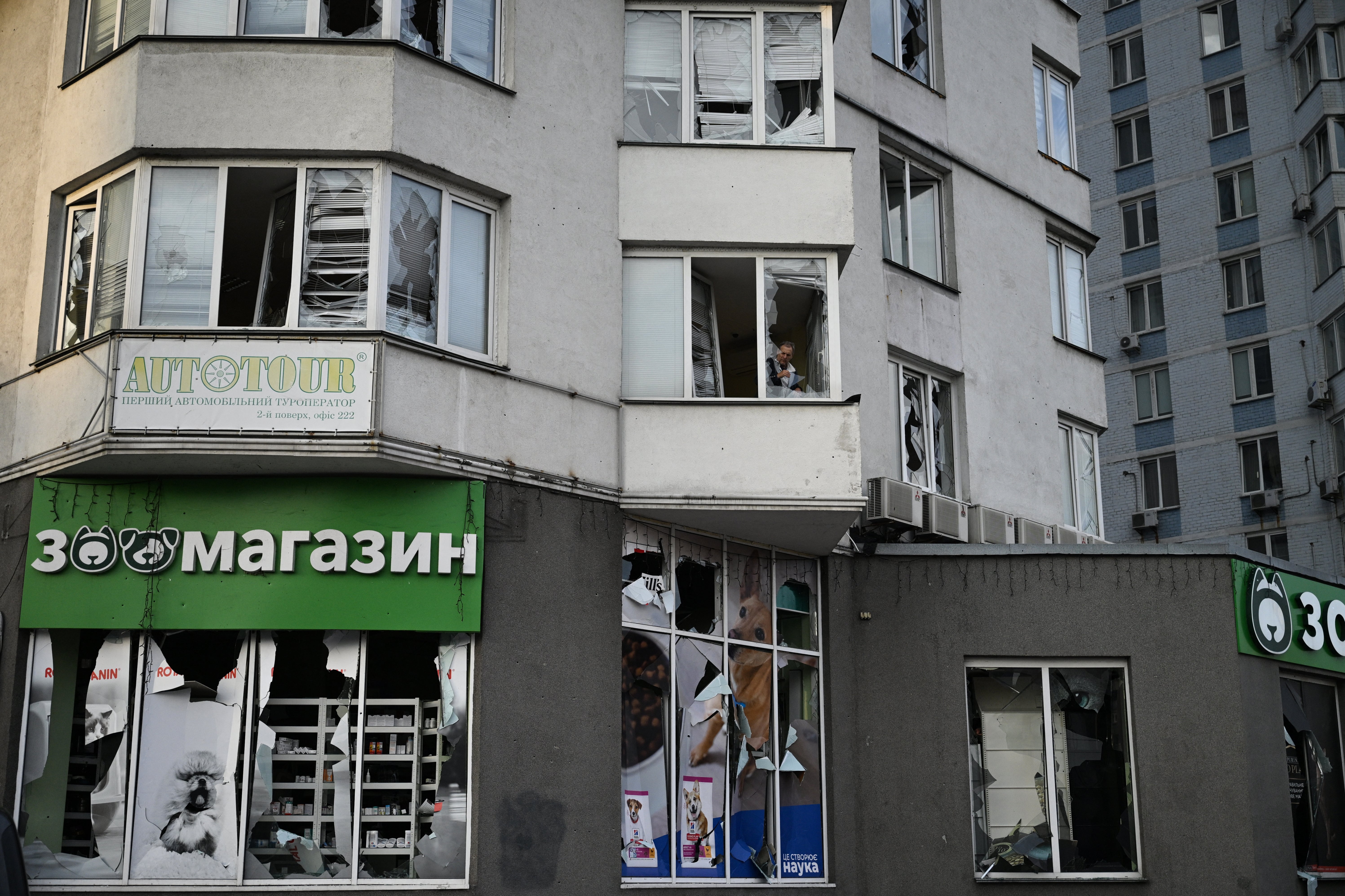 A resident clears shattered glass in a multistorey residential building