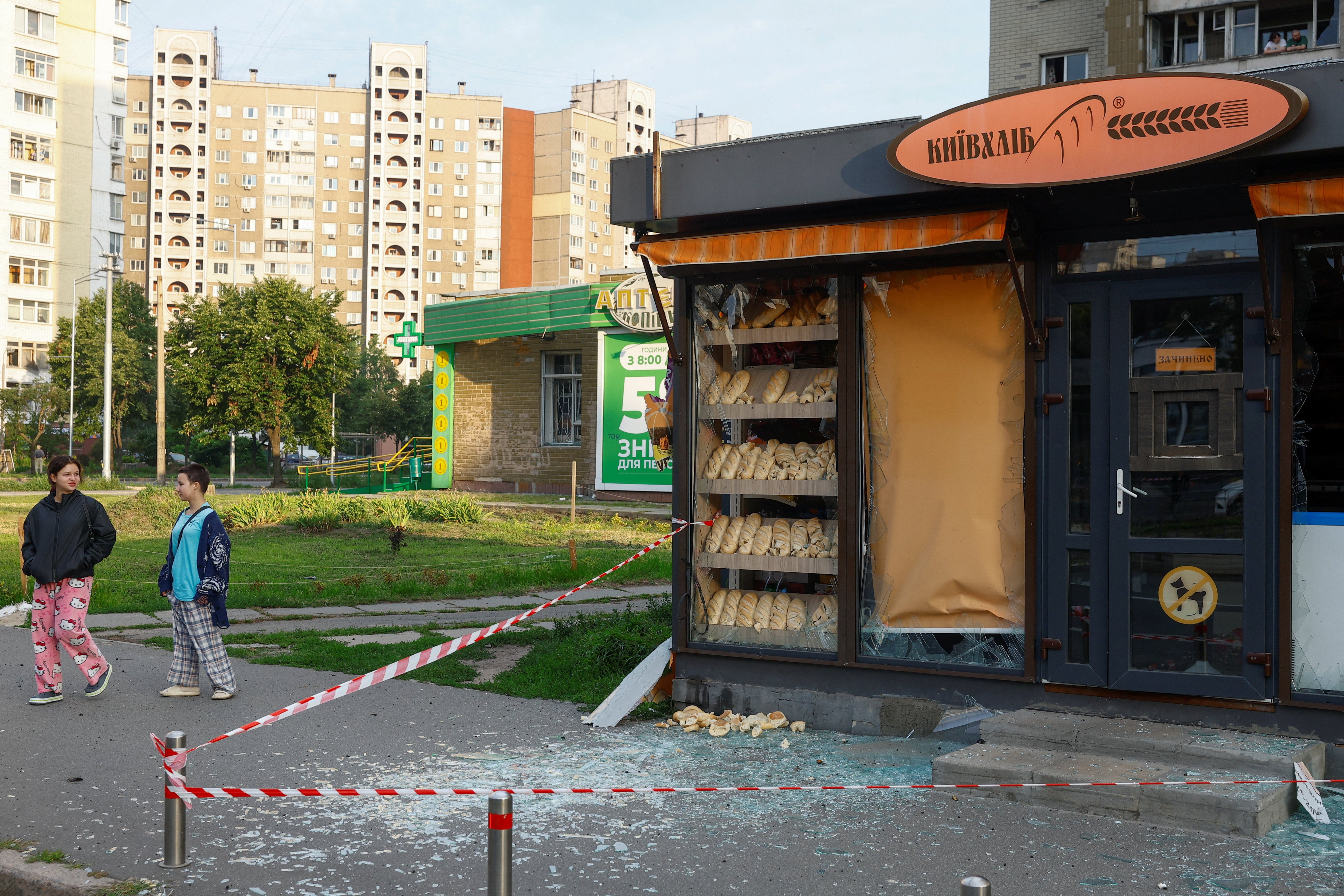 Teenagers walk next to a bakery shop damaged during Russian missile strike