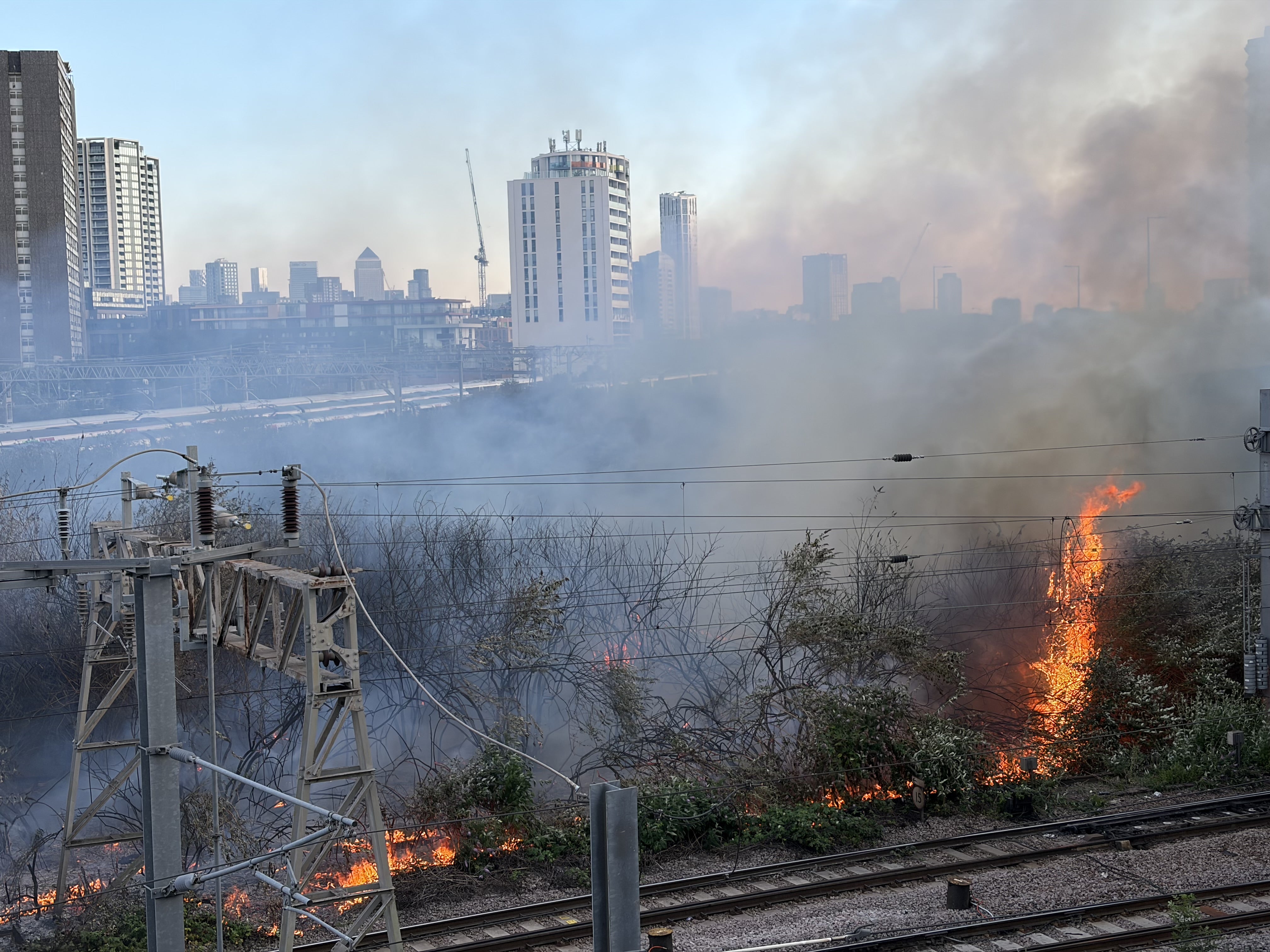 Shrubbery caught alight along rail lines near Stratford Station in east London on Friday (James Weech/PA)