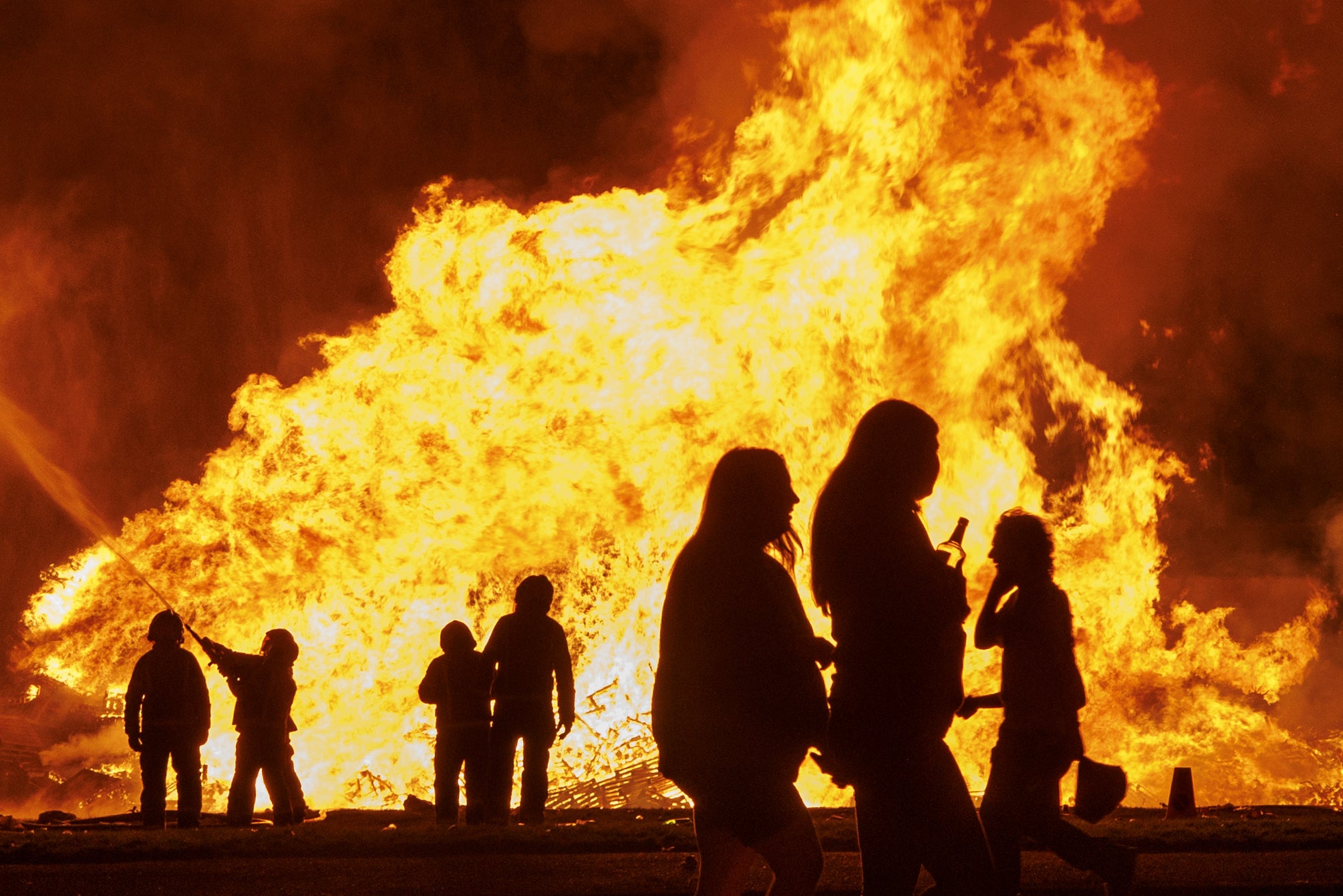 Members of the public watch the two Loyalist Corcrain Redmanville (LCR) bonfires in Portadown as part of the Twelfth of July celebrations (Liam McBurney/PA) (PA Wire)