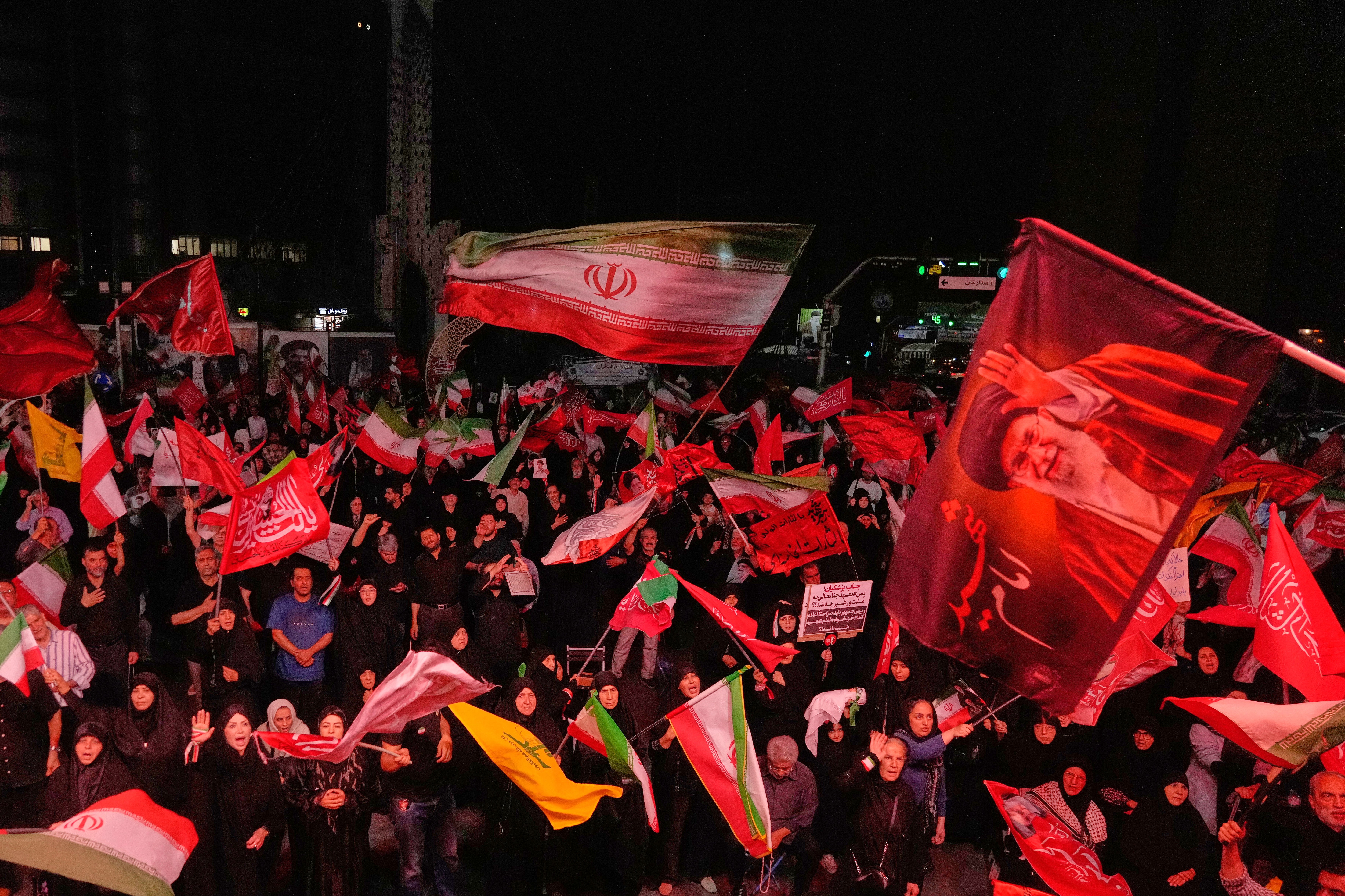 Pro-government demonstrators wave Iranian and religious flags in a gathering commemorating the late Iranian Supreme Leader Ayatollah Ali Khamenei, shown in a flag at right, at a square in Tehran, Saturday, July 11, 2026. (AP Photo/Vahid Salemi)
