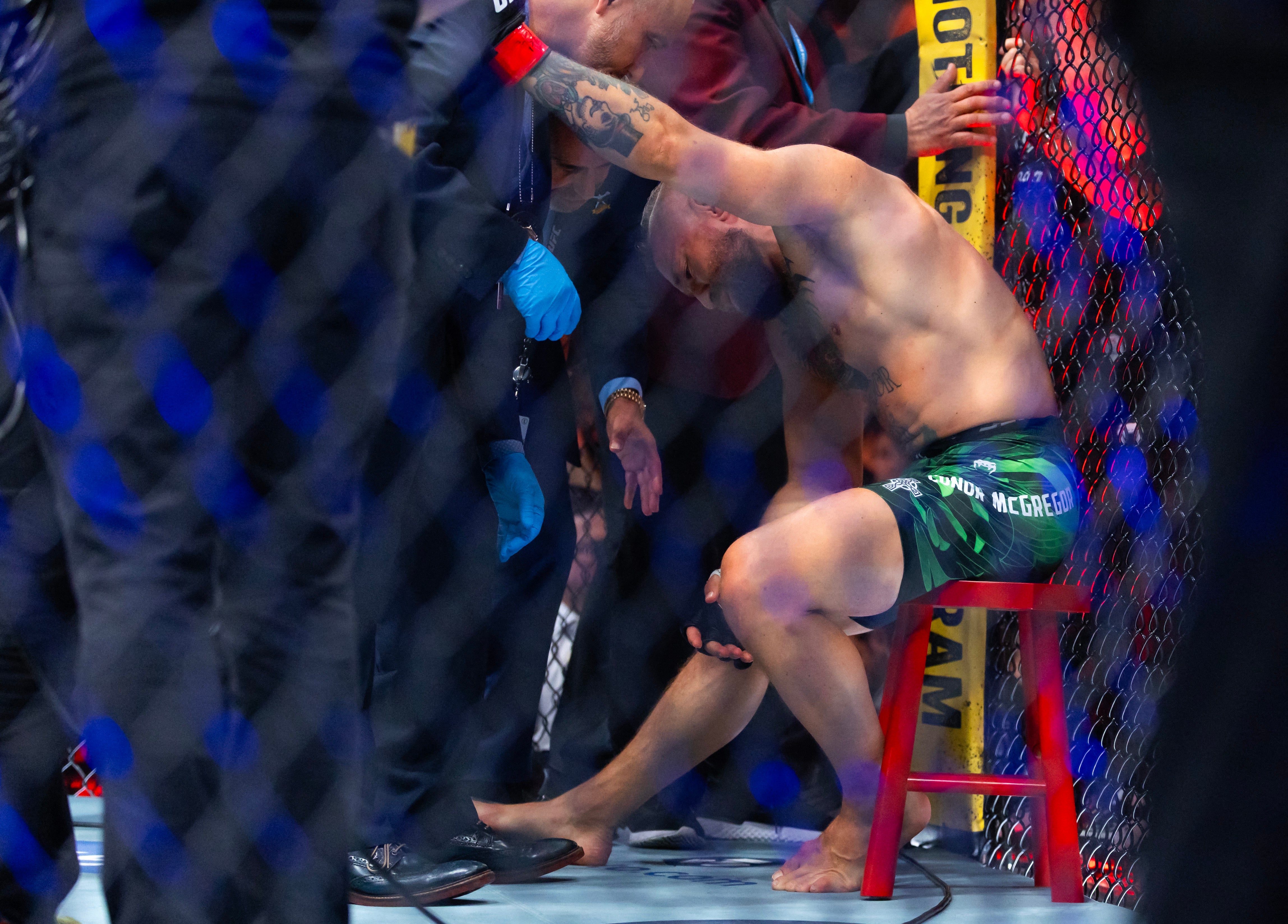 Conor McGregor reacts after suffering an injury the ended his fight with Max Holloway