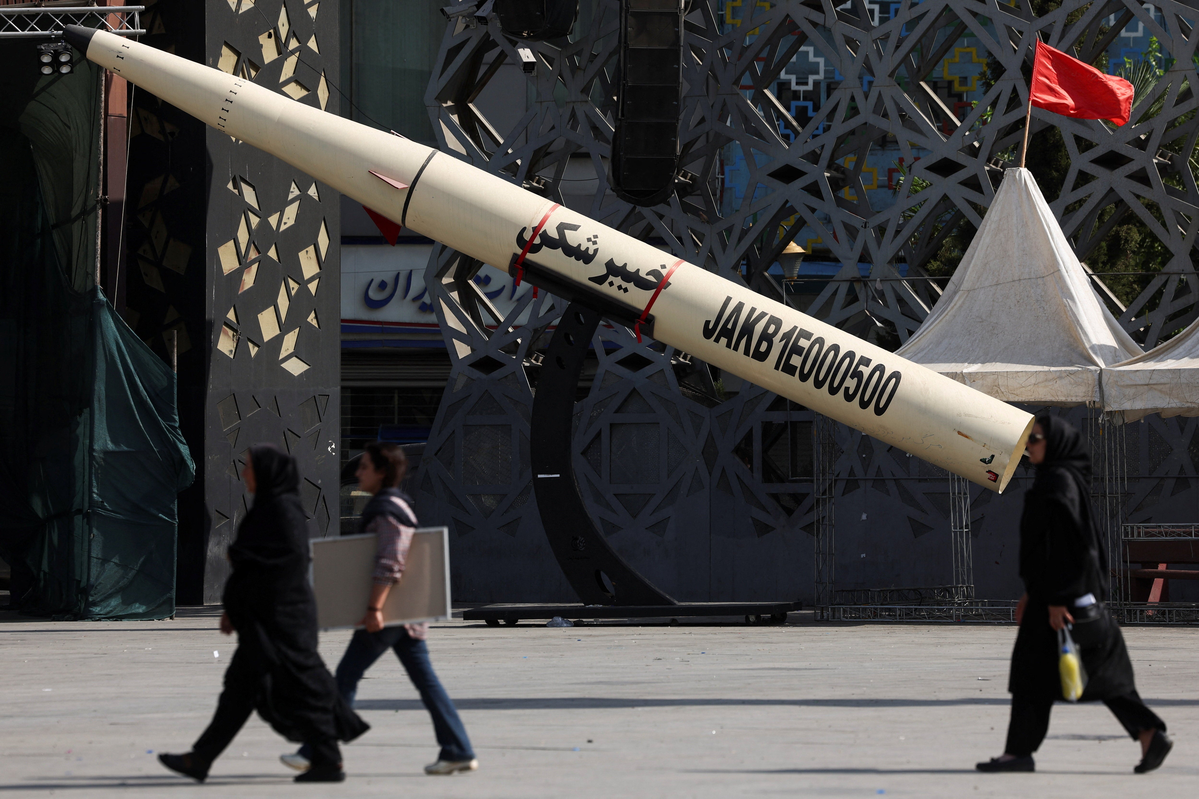 People walk next to a symbolic mockup of an Iranian missile at Imam Hussein Square in Tehran (Reuters)