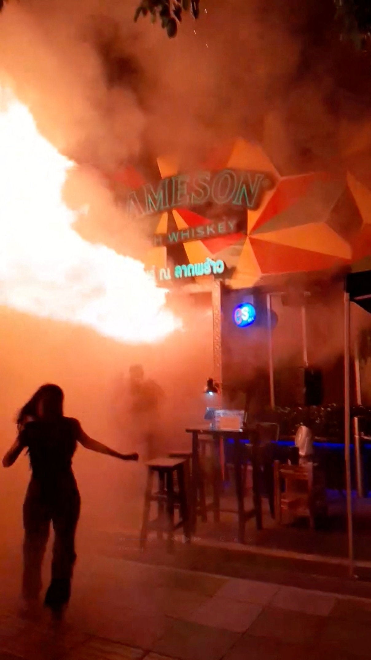 People run as flames rise at a pub in Bangkok, Thailand