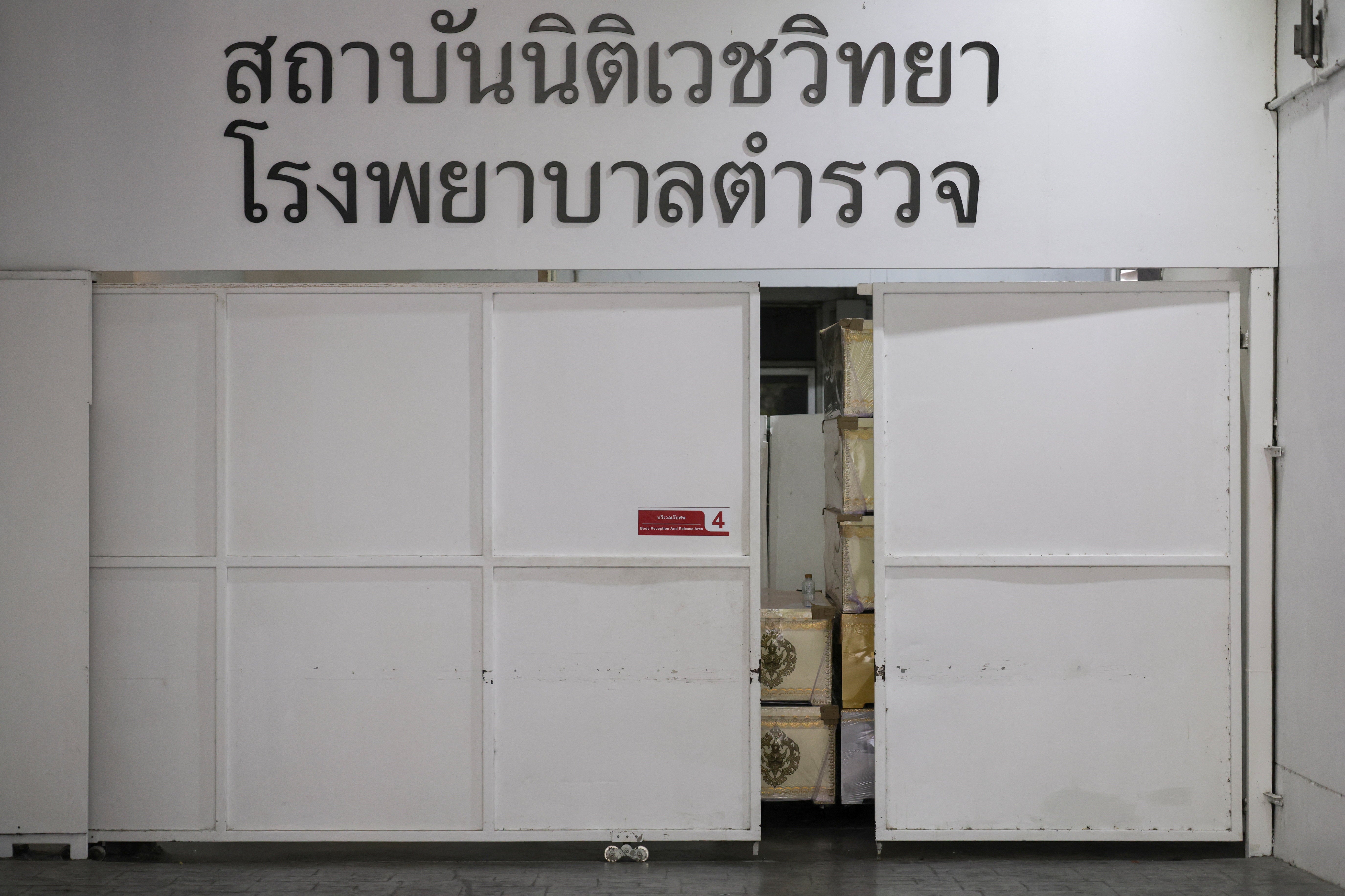 Coffins sit behind a door at the Police Hospital morgue following a deadly fire at a pub in Bangkok, Thailand