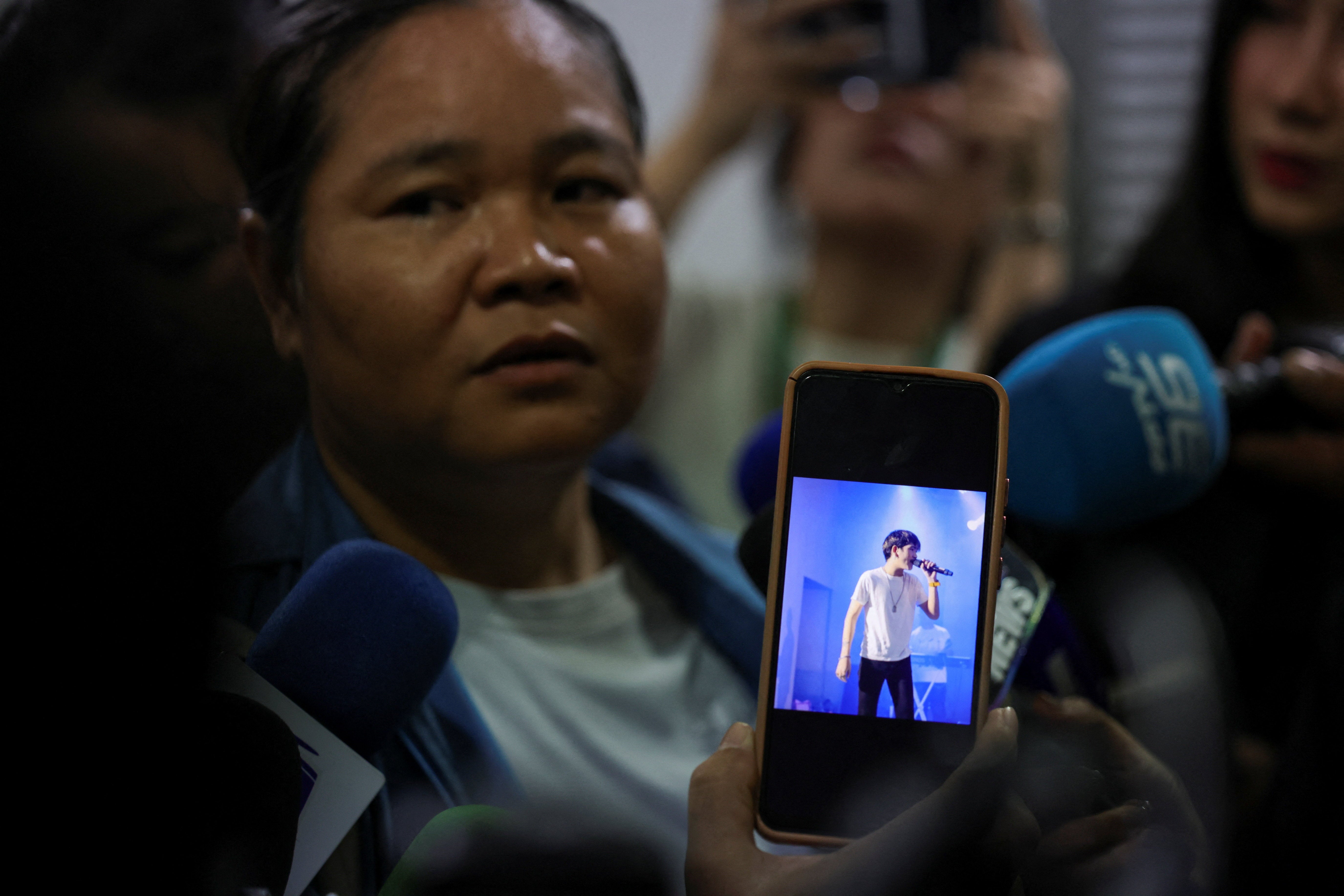 A woman shows the photo of her son, who has been missing, while talking to the members of the media at the Police hospital morgue, following a deadly fire at a pub, in Bangkok (Reuters)