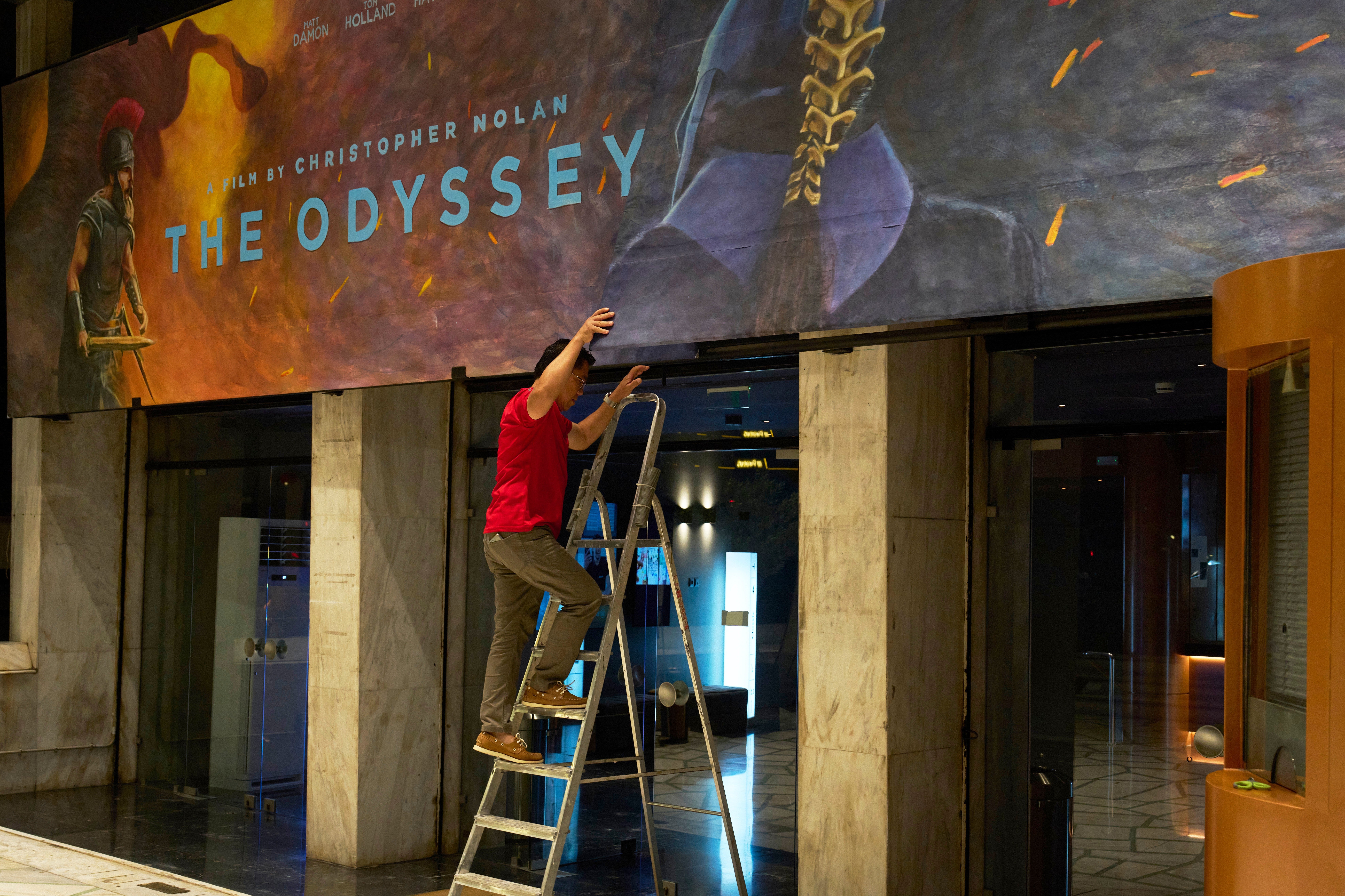 A worker installs a hand-painted billboard, painted by artist Virginia Axioti, for Christopher Nolan's upcoming film "The Odyssey," starring Matt Damon as Odysseus, outside Athens' Athinaion cinema, where every film is promoted with a hand-painted billboard