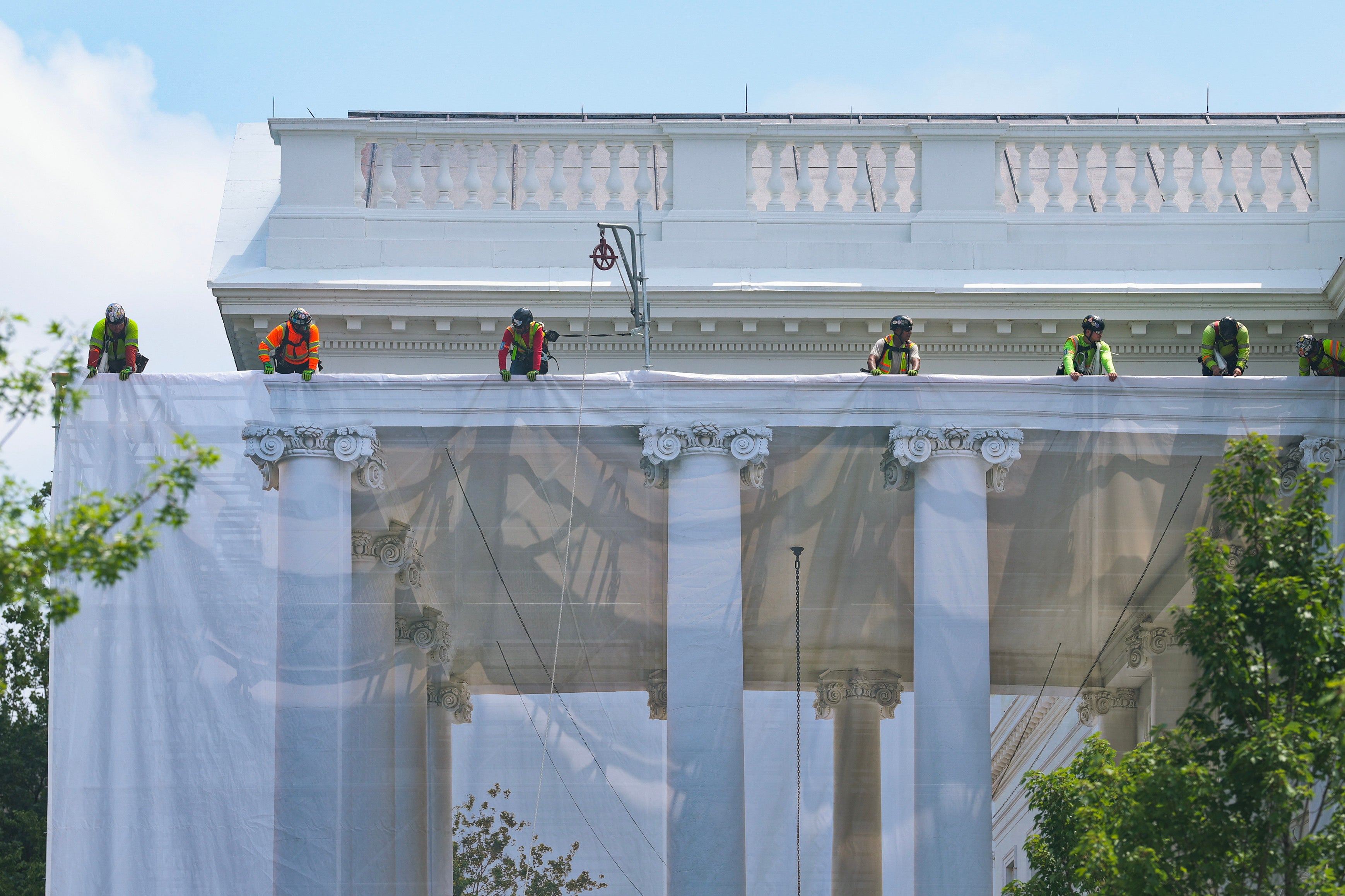 Construction workers placed a tarp over the scaffolding that surrounds the columns at the North Portico of the White House displaying a photorealistic image meant to mimic the finished product — and even the sky through the columns