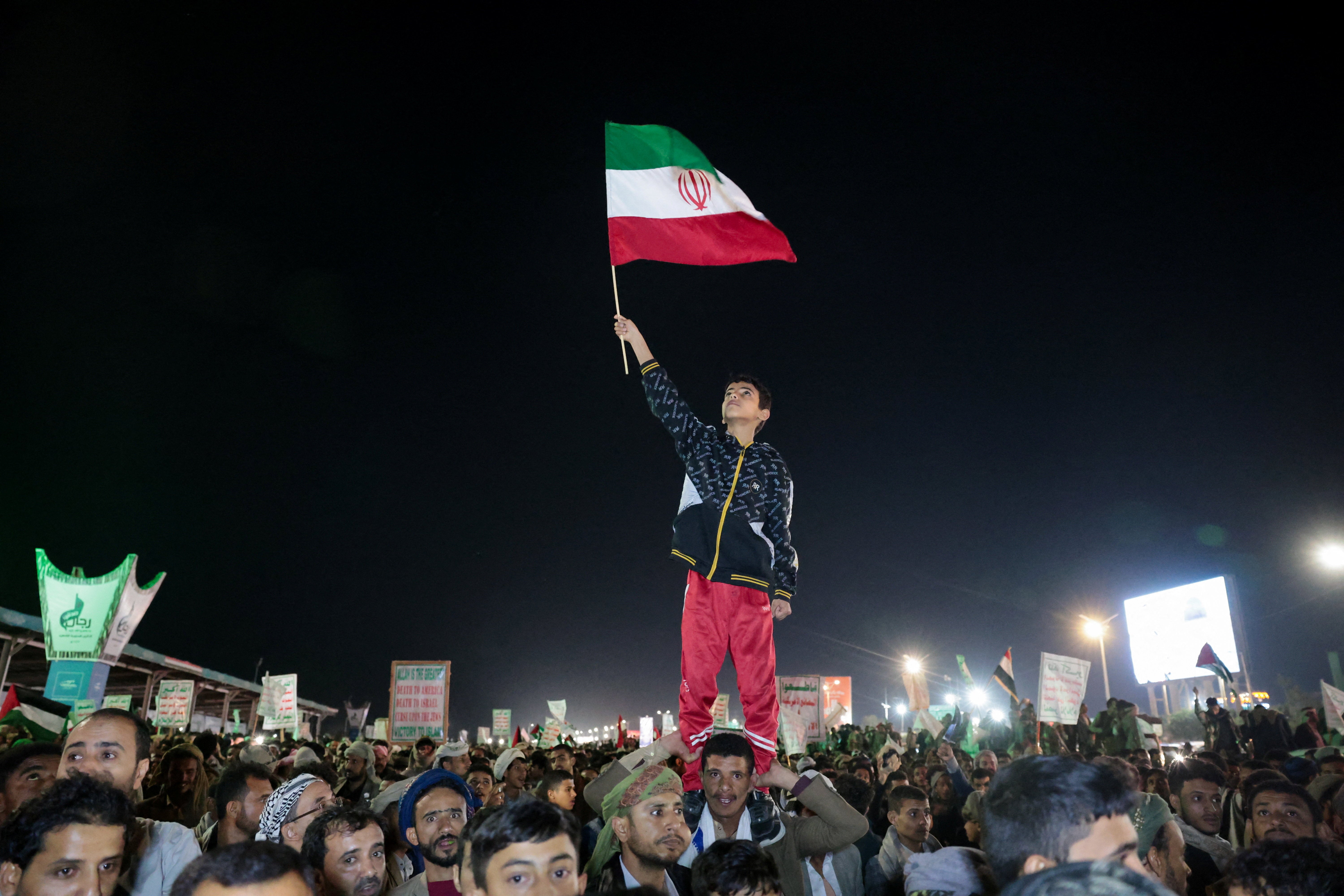 A boy waves an Iranian flag as he joins Houthi supporters as they demonstrate against airstrikes on Sanaa International Airport (Reuters)