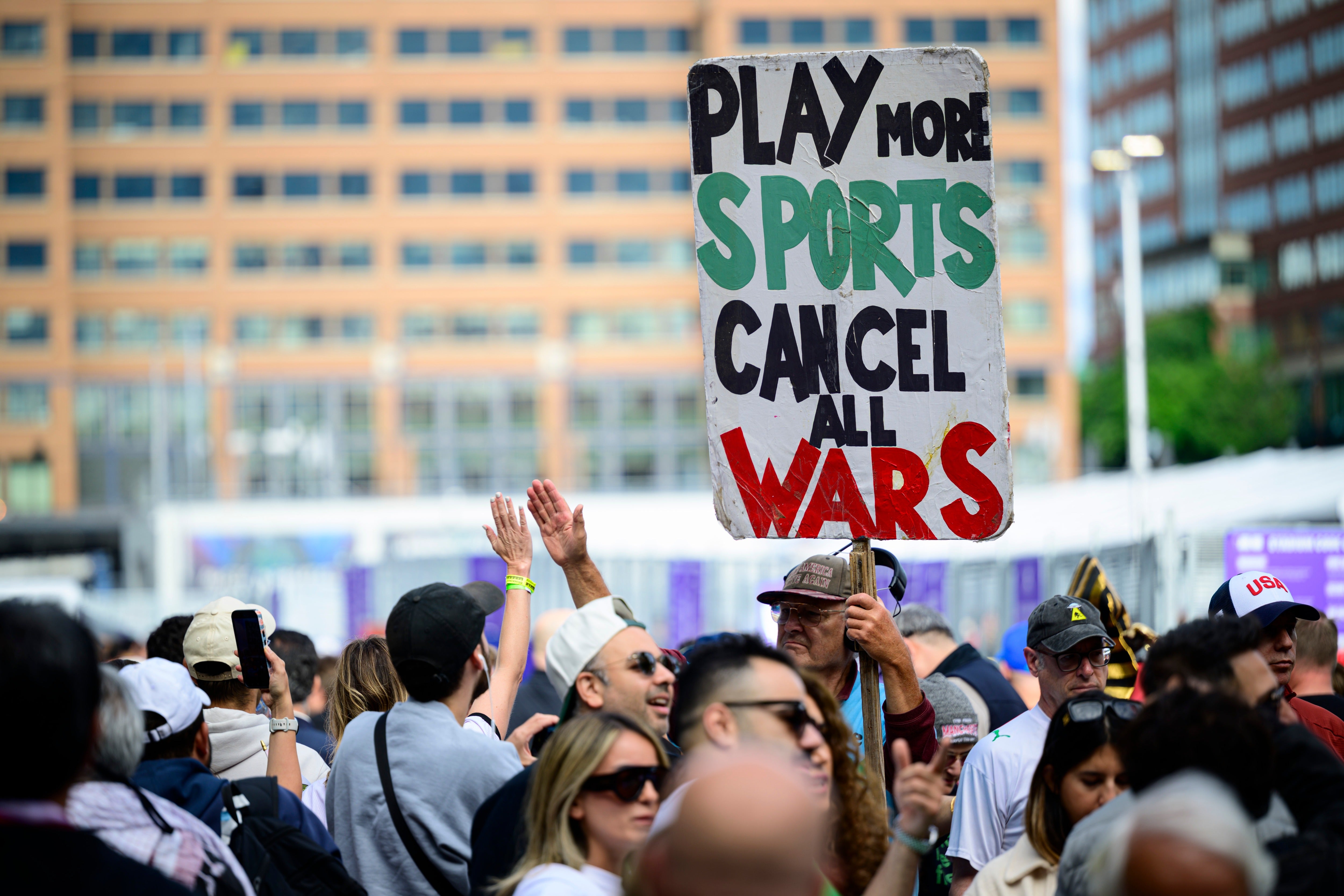 A man holds a ‘Play no Sports, Cancel all Wars’ placard outside Lumen Field