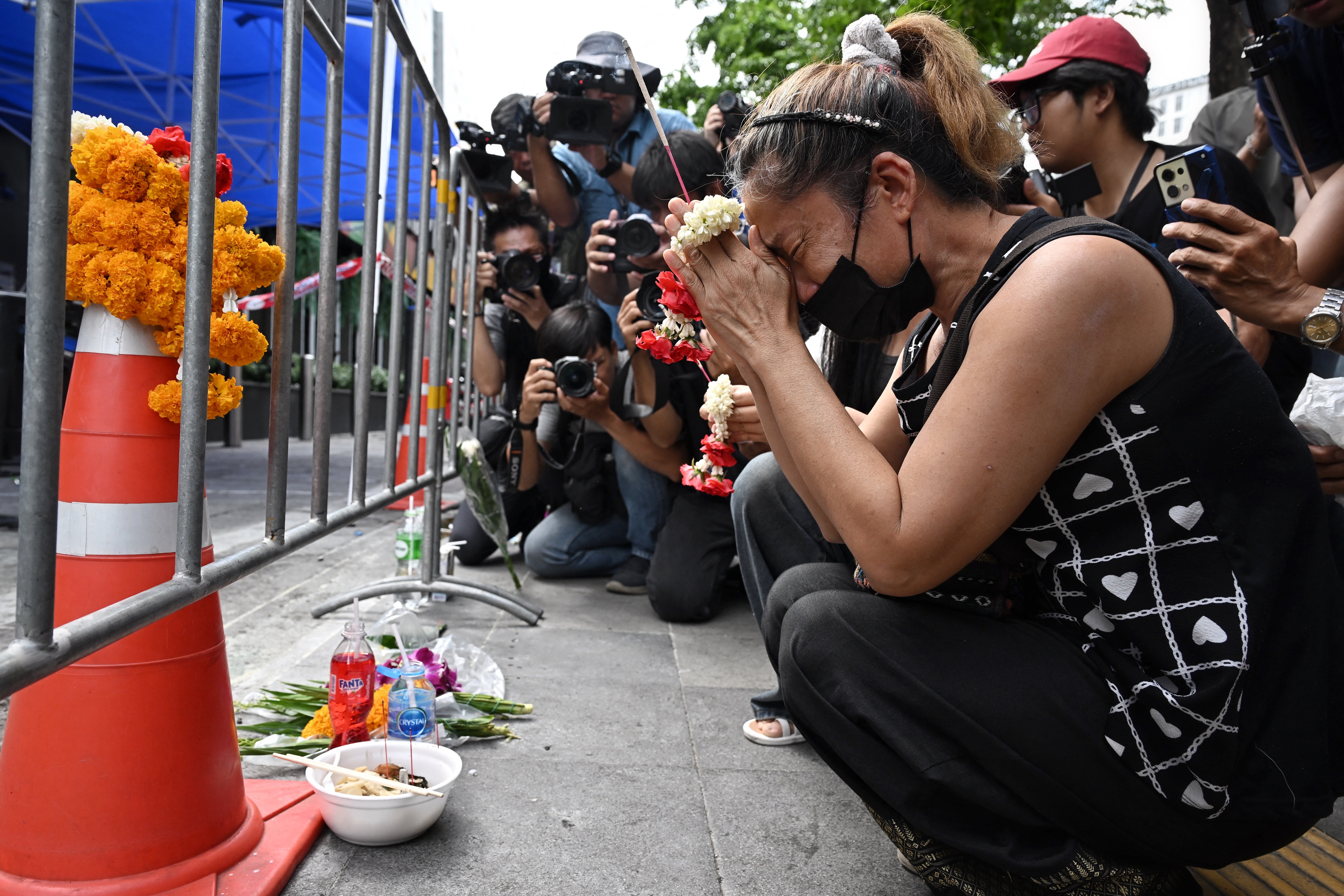 A woman, identified as Nid, prays for her deceased daughter Namtip Tubsook and her son-in-law Suwitcha Sirililung in front of the Rong Beer Na Lat Phrao bar.