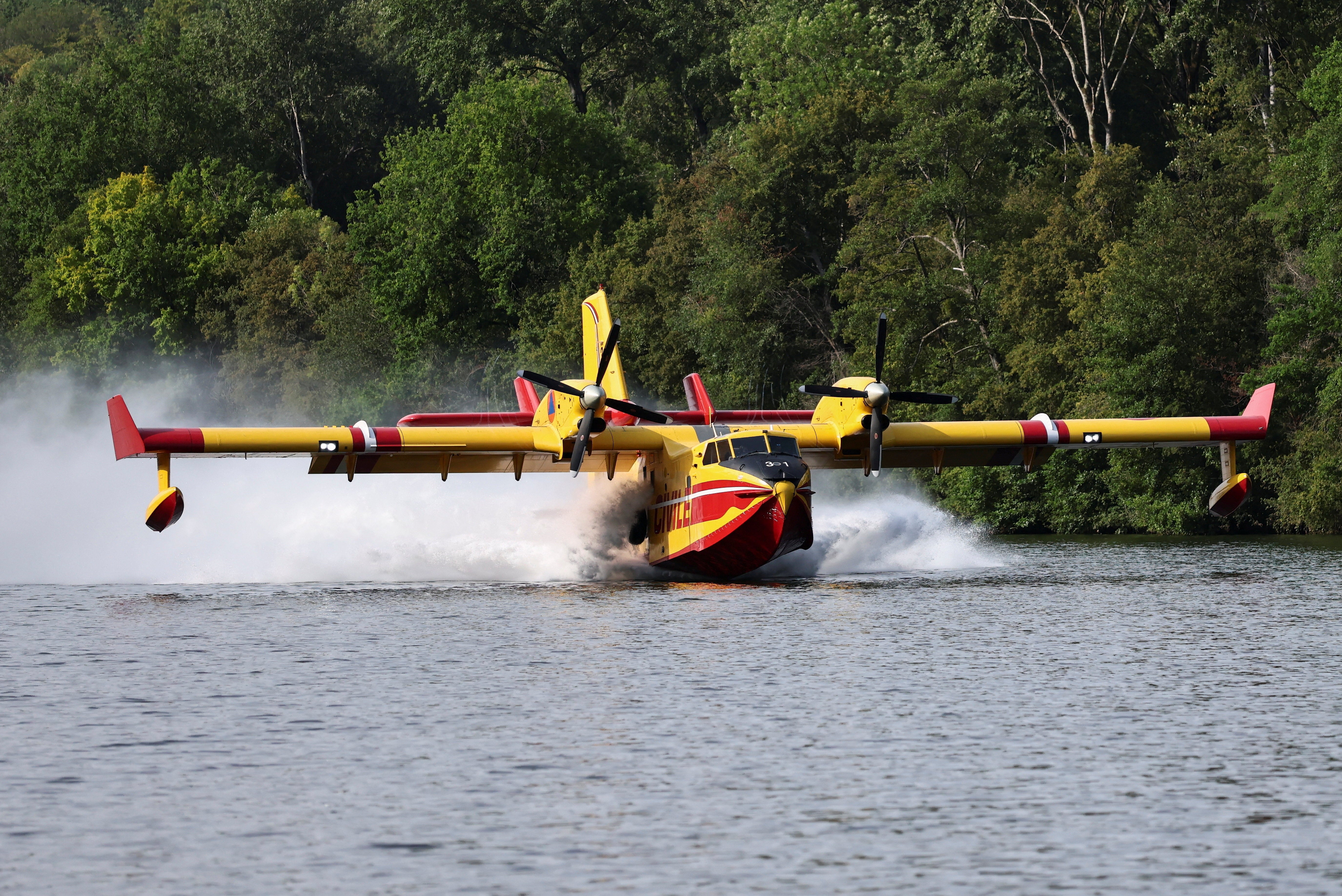 A firefighting Canadair aircraft skims the surface of the Seine River while collecting water in Ivry-sur-Seine, to assist efforts against a wildfire in the Fontainebleau forest during a heatwave affecting large parts of the country, near Paris, France, July 14, 2026.