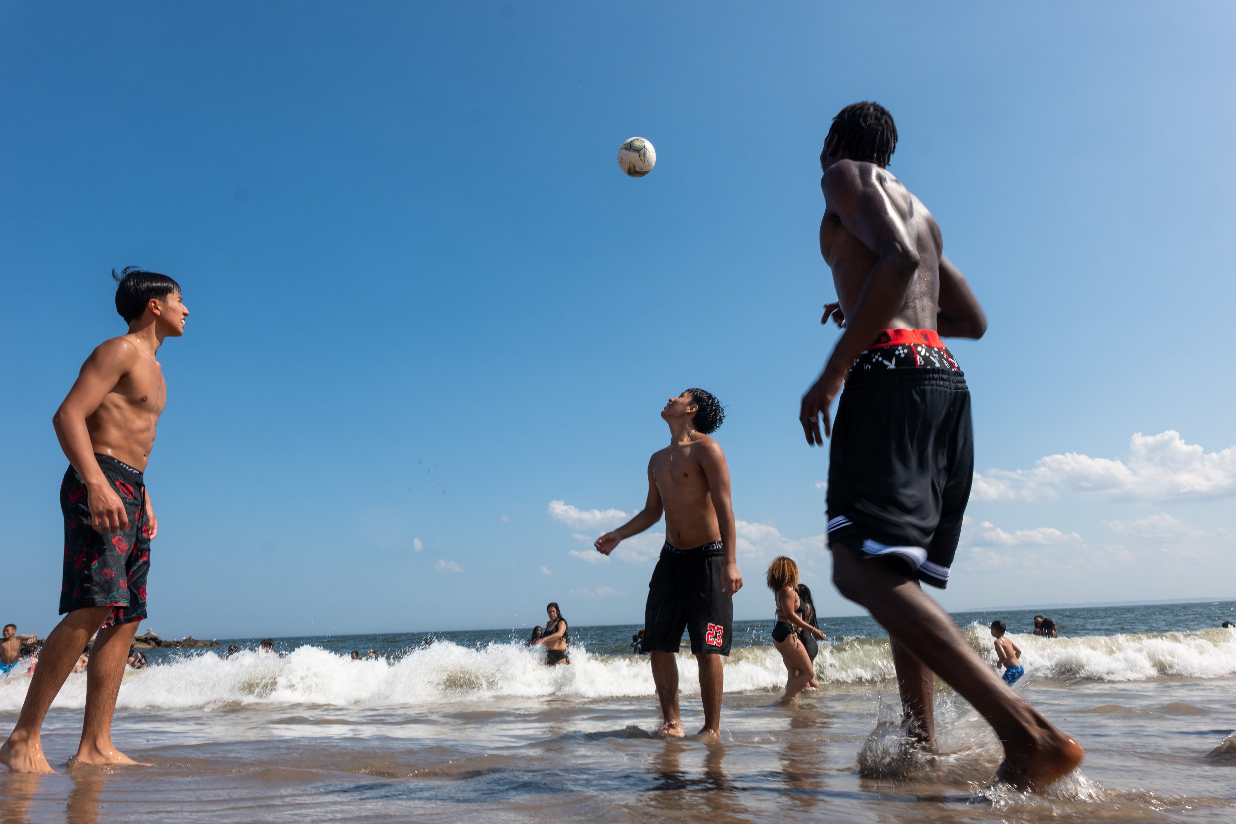 A group of teens play soccer at the beach at New York City’s Coney Island earlier this month. Experts say using happier images to tell stories about deadly heat can leave readers confused about the severity of its effects