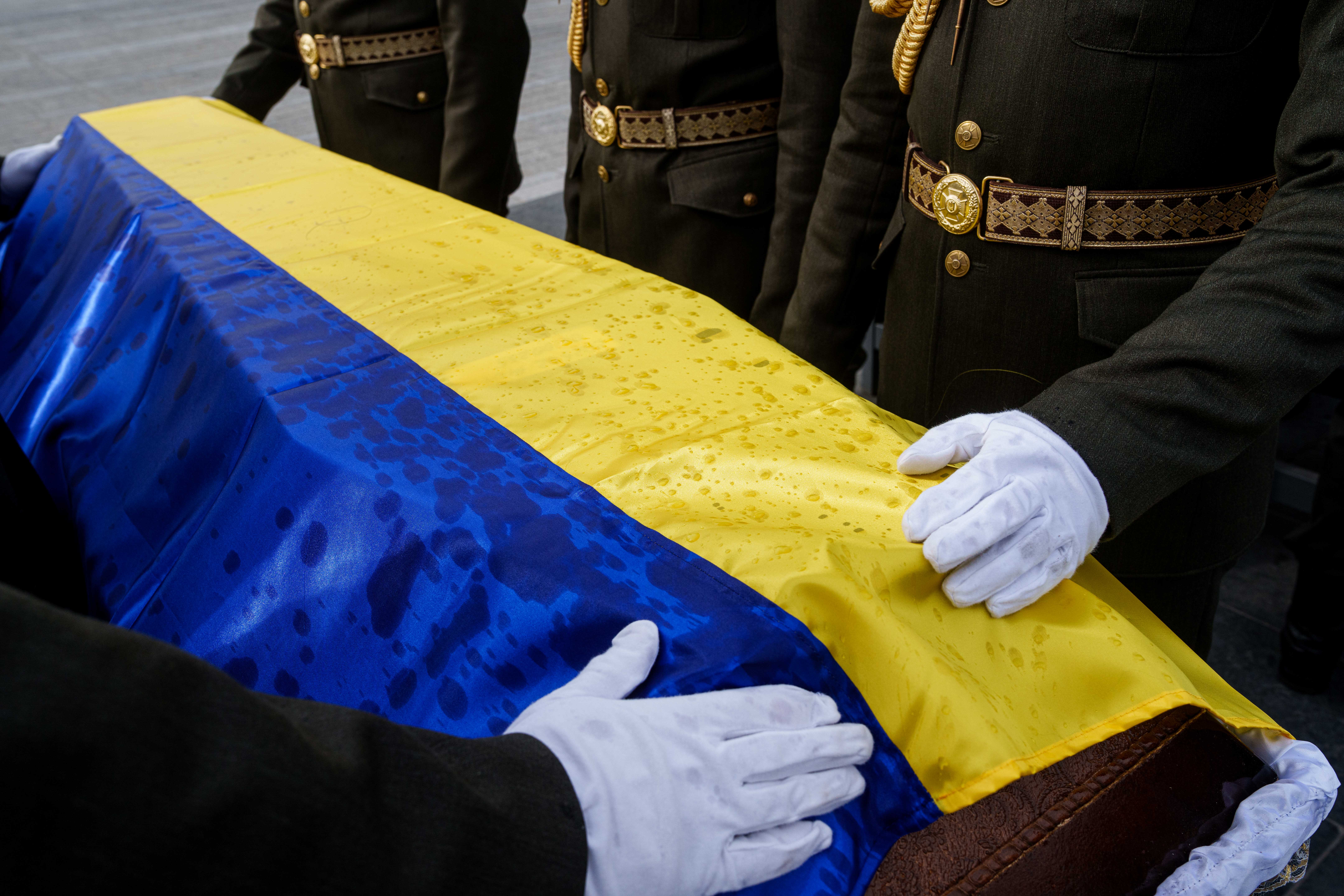 An honor guard straightens out the flag draped over the coffin of a unidentified Ukrainian soldier killed in battle during the Russian-Ukrainian war (AP Photo/Evgeniy Maloletka)