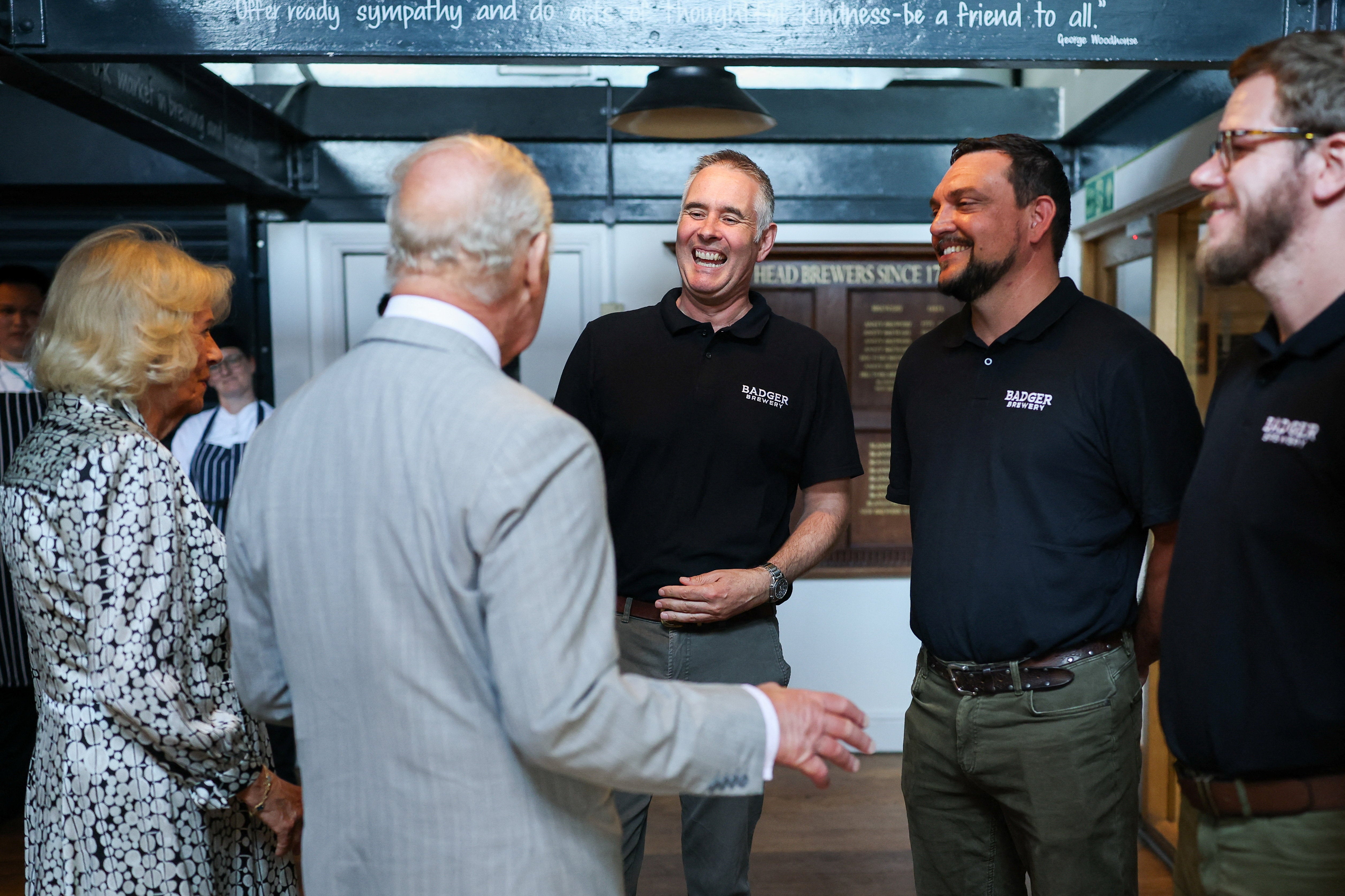 King Charles III and Queen Camilla speak with head brewer Toby Heasman and other staff