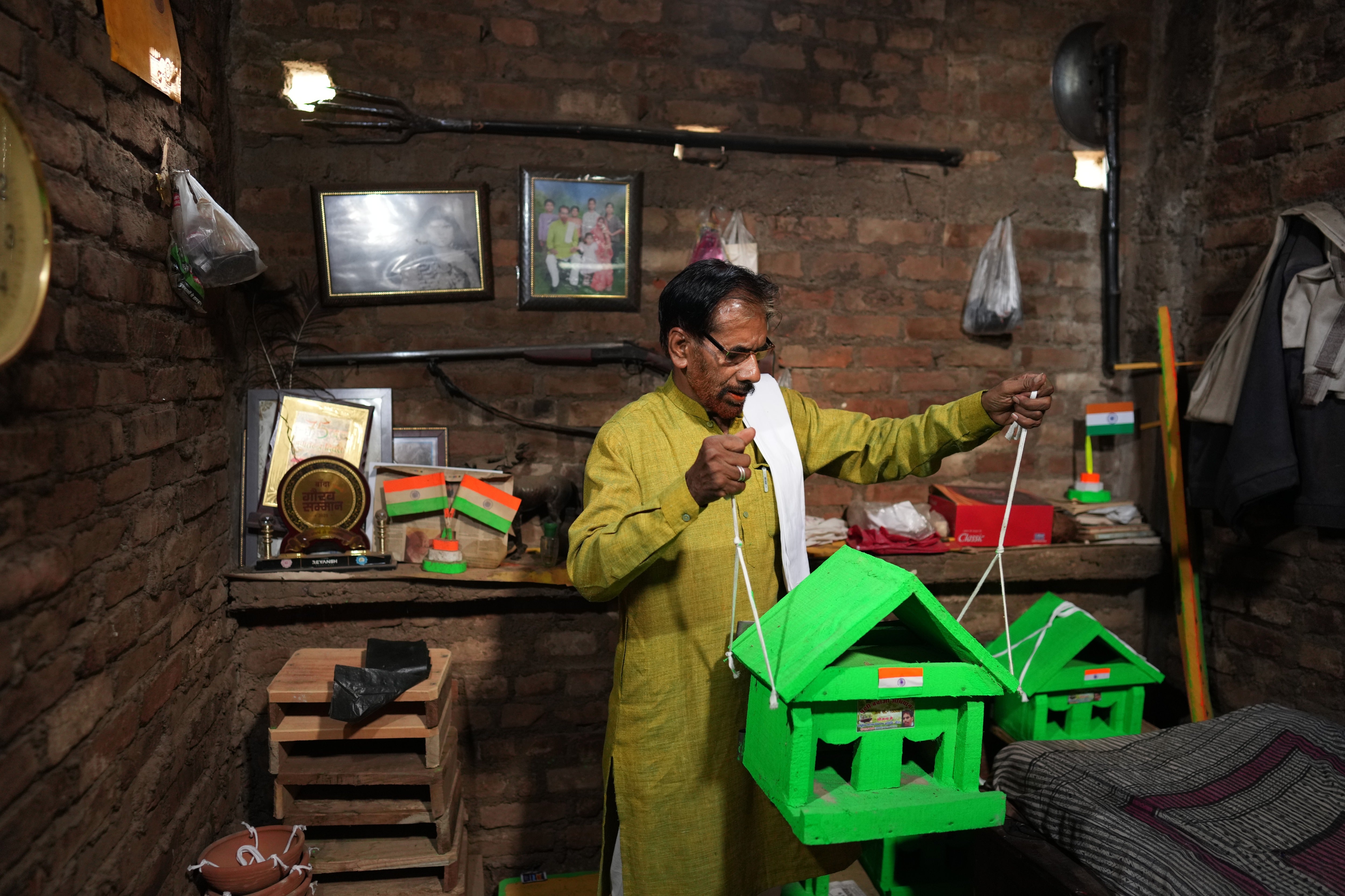 Bird conservationist Shobharam Kashyap holds wooden birdhouses he makes for sparrows during a heat wave in Banda