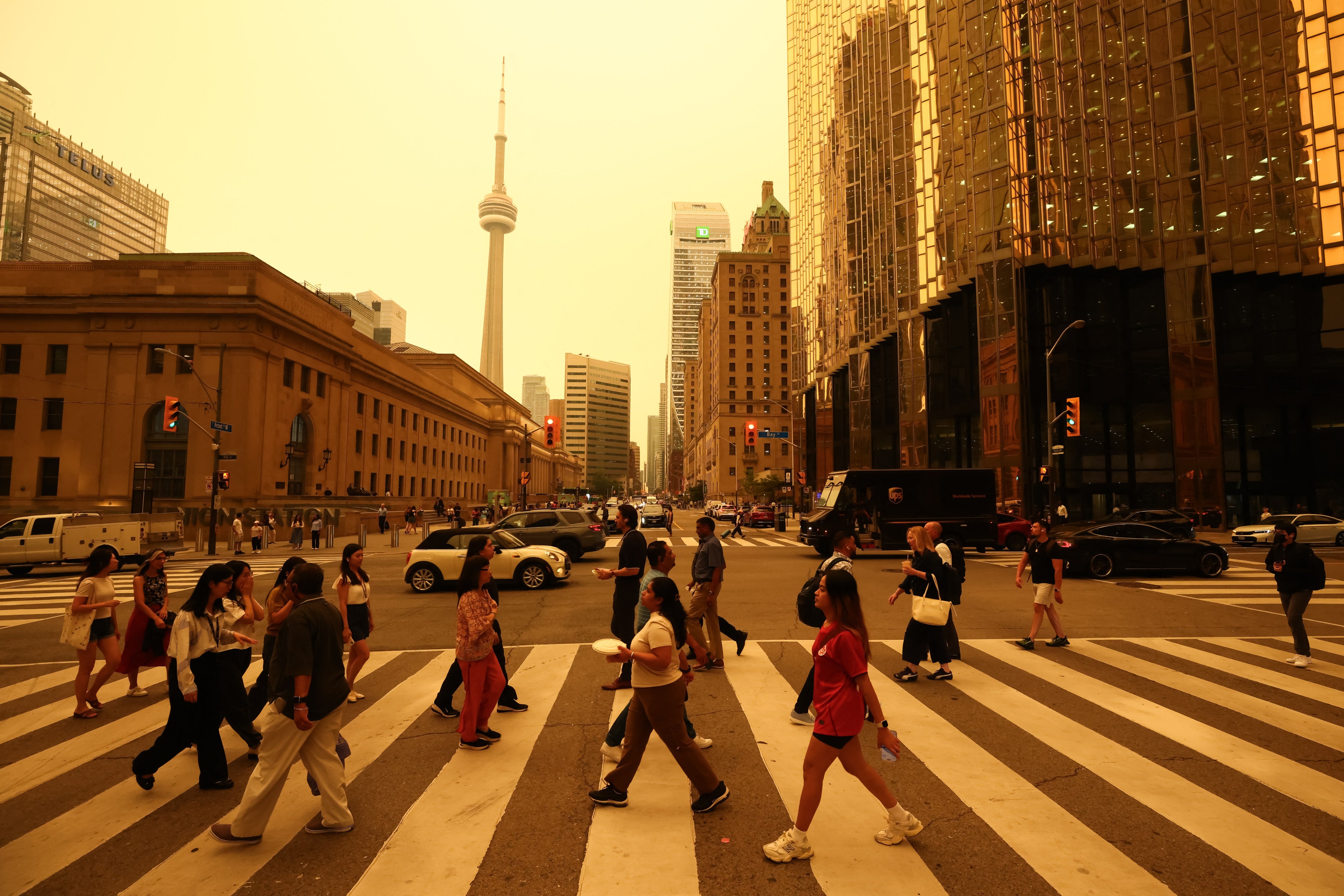 People walk in downtown Toronto, as smoke from forest fires in Northern Ontario causes poor air quality over the city, in Toronto, Ontario, Canada, July 15, 2026